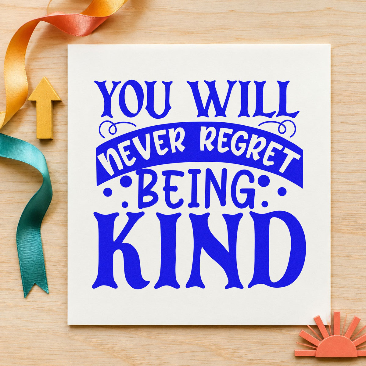 Never Regret Being Kind craft stamp imprinted in blue ink on paper, a design suited to framed pass window.