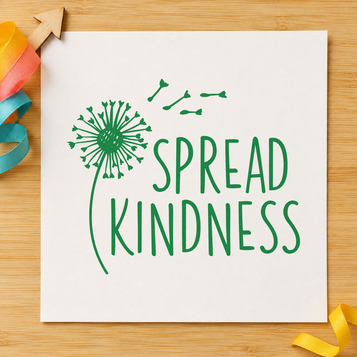 Spread Kindness Dandelion Seeds craft stamp imprint in green ink on a handmade project, one idea being kindness rock cards.