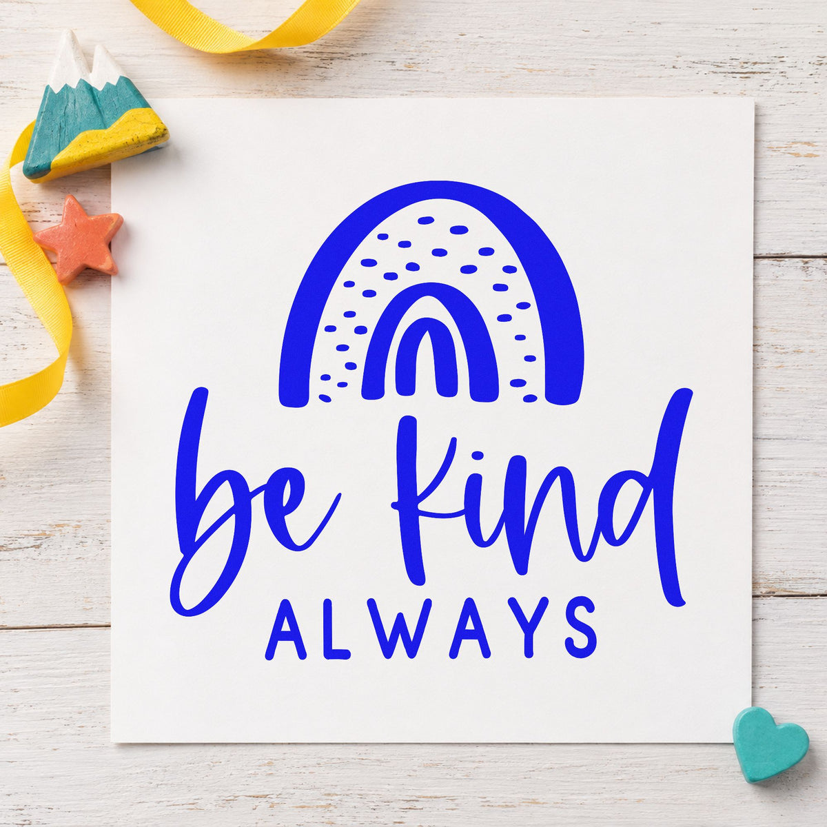 Be Kind Always Rainbow craft stamp imprinted in blue ink on paper, a design suited to framed sign in table.