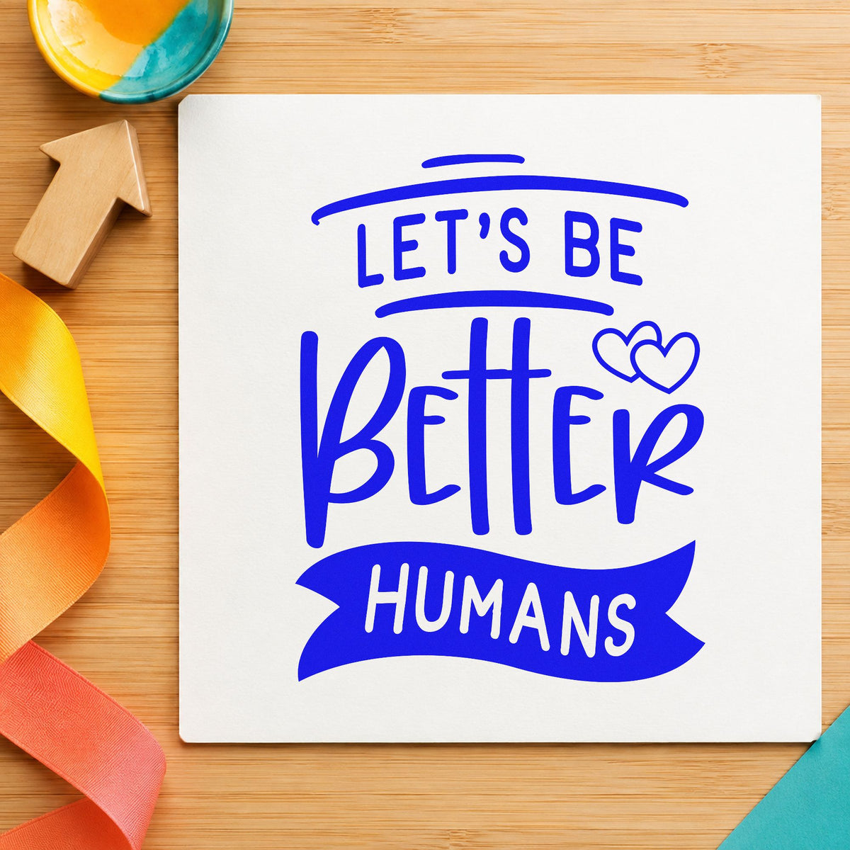 Let's Be Better Humans craft stamp imprinted in blue ink on paper, a design suited to framed break room.