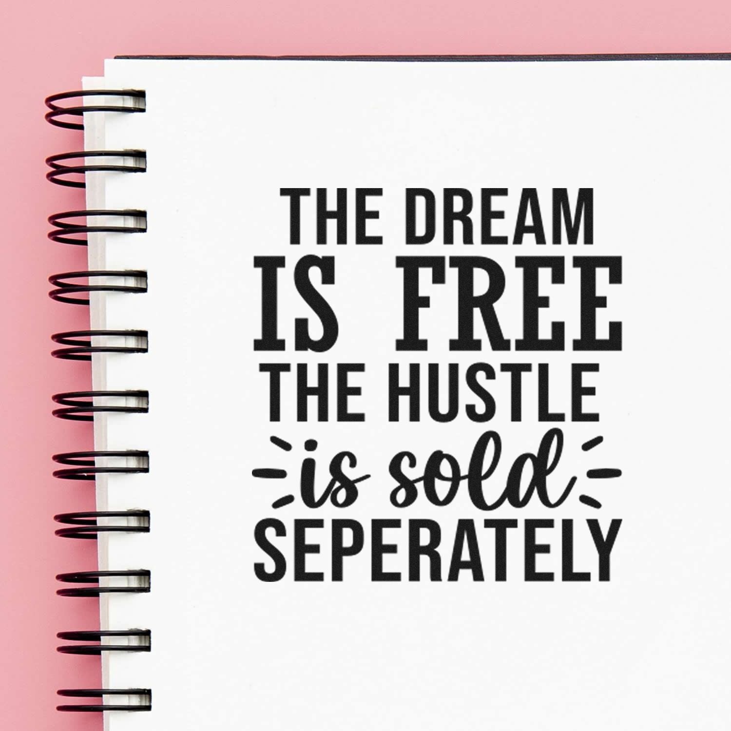 Motivational rubber stamp design on notebook page reads, The dream is free, the hustle is sold separately.