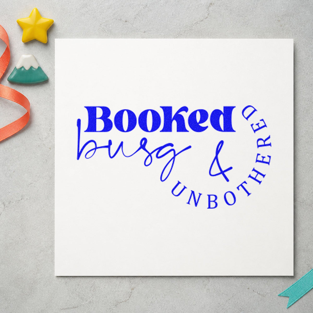 Booked Busy And Unbothered craft stamp imprinted in blue ink on paper, a design suited to framed station mirror.