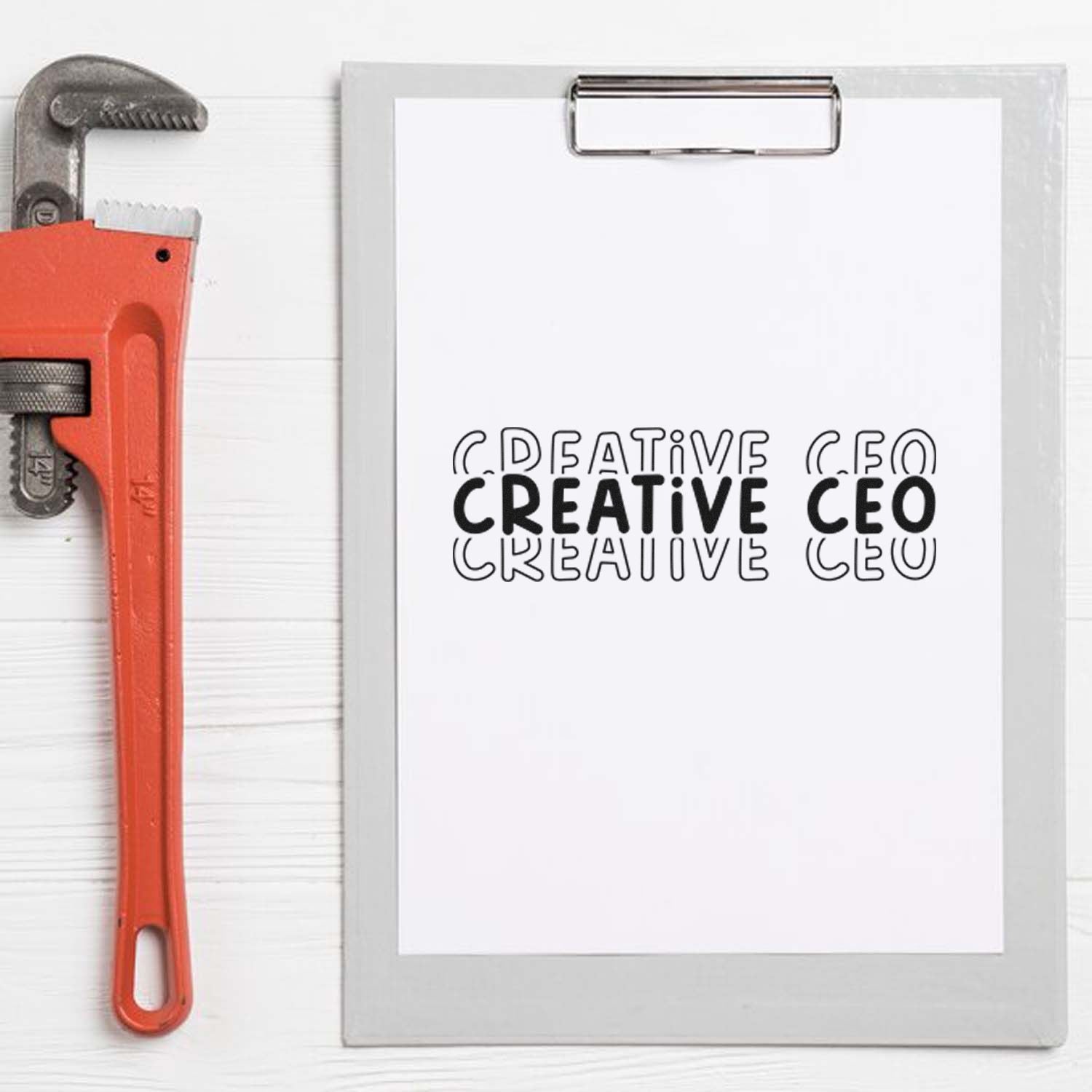 Creative CEO custom rubber stamp on clipboard beside adjustable pipe wrench, perfect for office branding and handmade business use.
