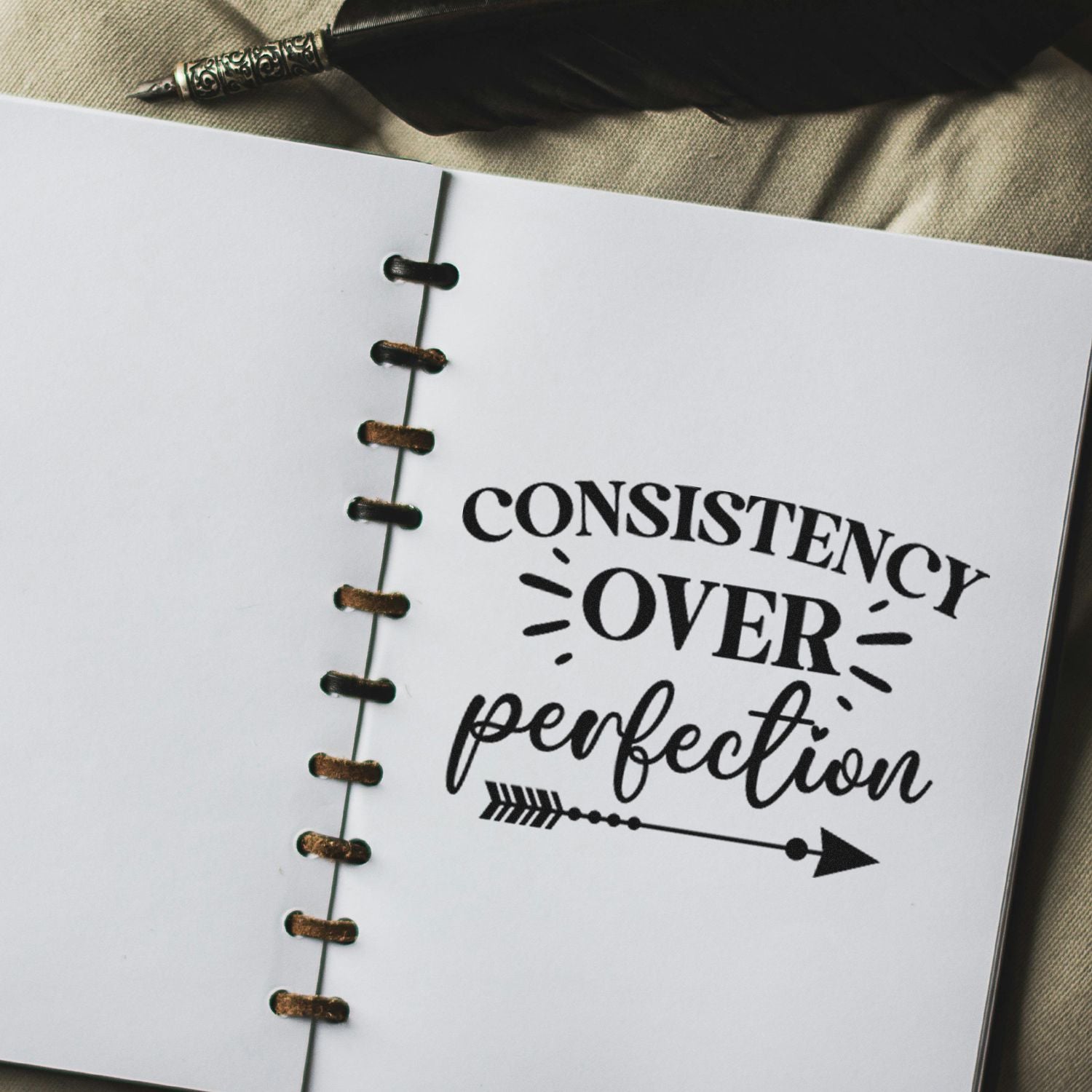 Motivational rubber stamp design reading Consistency over perfection on a notebook page for journaling and planning.