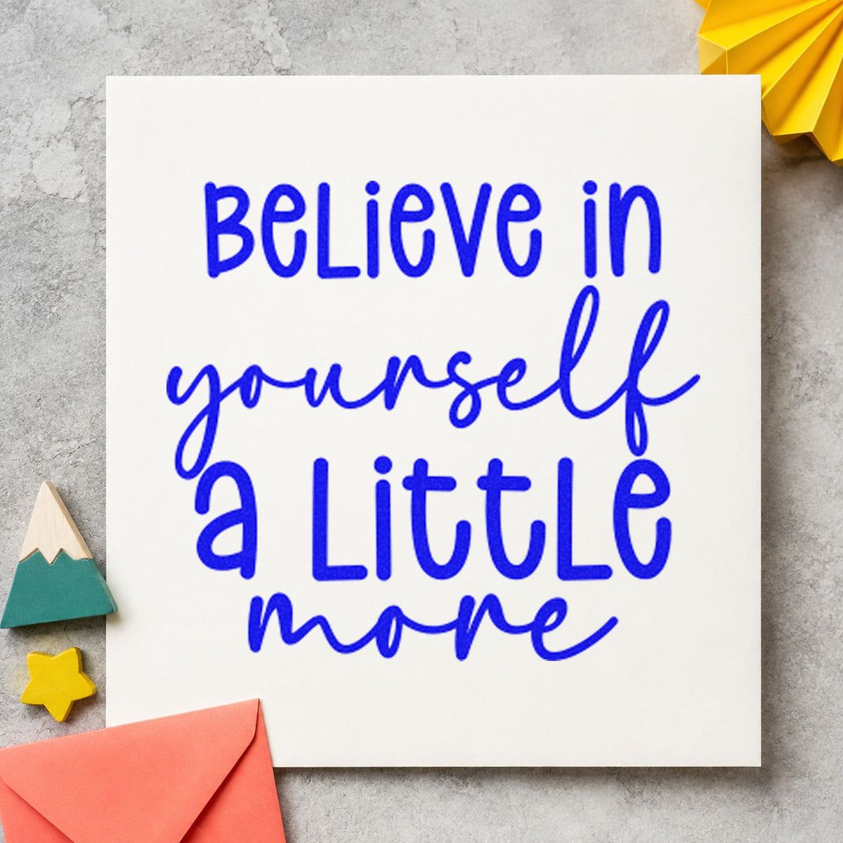 Believe Yourself A Little More craft stamp in blue ink on cardstock, an easy option for clicker pouch printing.