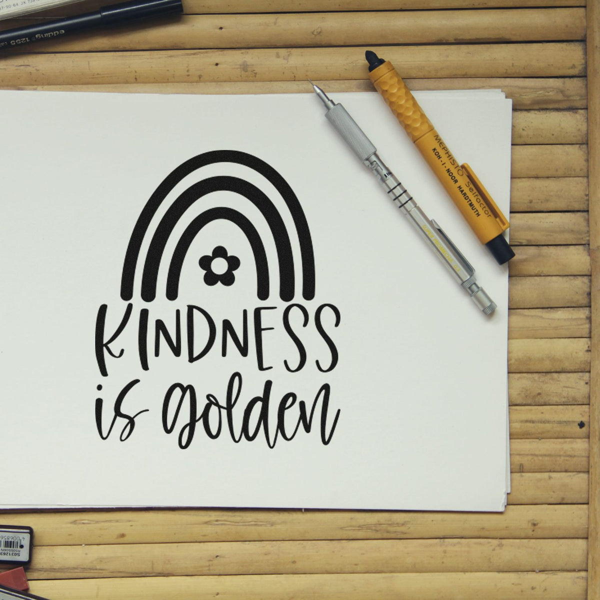 Kindness Is Golden Rainbow Floral Accents Stamp - Premium Vintage Pro Wooden imprint stamped in black ink. A rainbow with a small flower appears above the words "Kindness is golden."