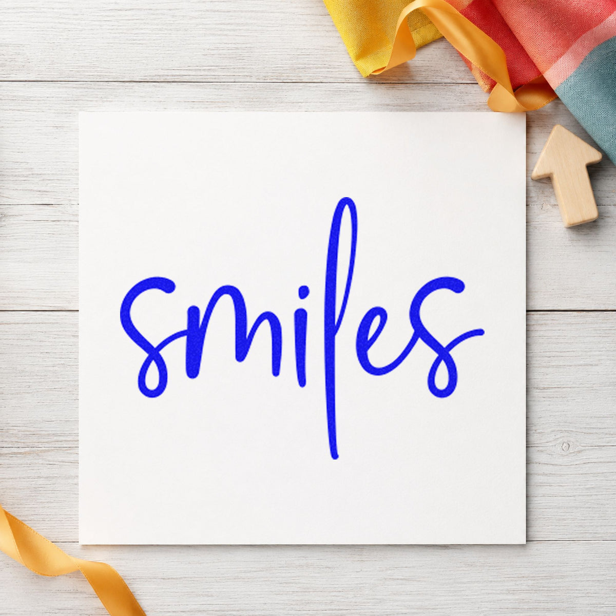 Smiles Simple Brush Script craft stamp in blue ink on cardstock, an easy option for backdrop panel printing.