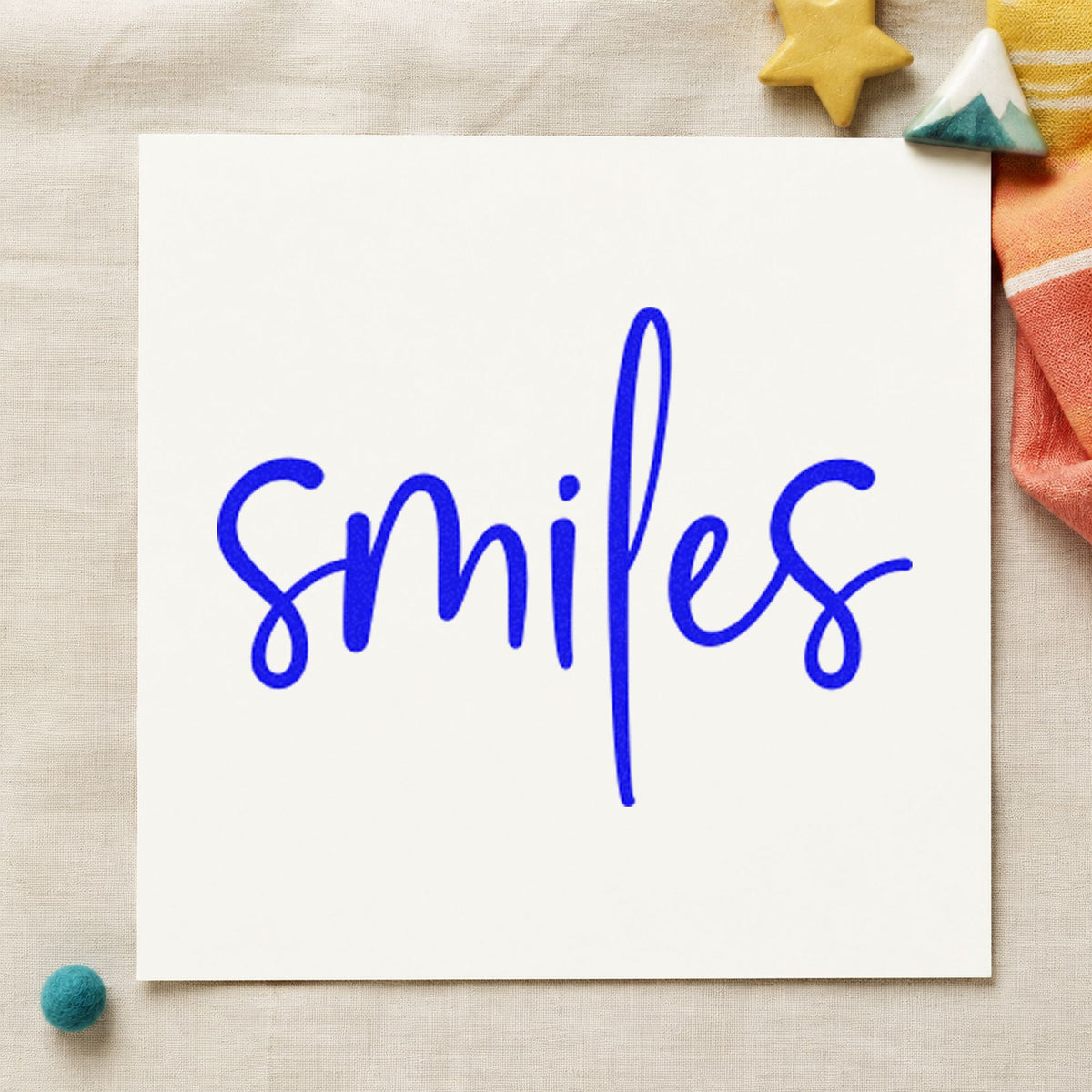 Smiles Simple Brush Script craft stamp imprinted in blue ink on paper, a design suited to framed booth front.