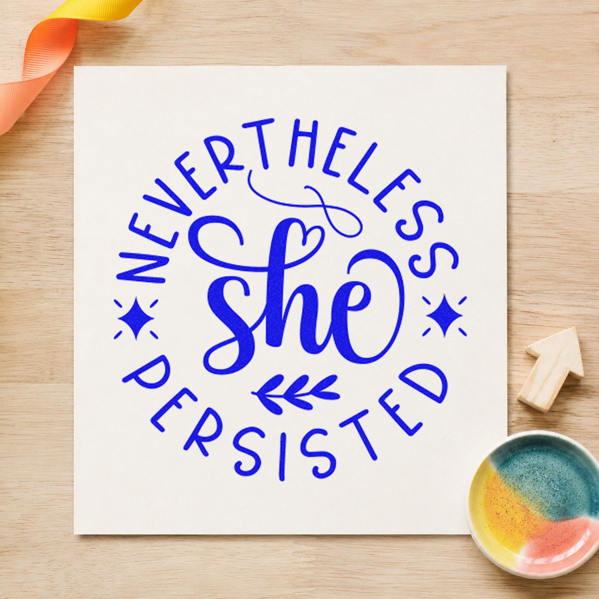 Nevertheless She Persisted Circle craft stamp imprinted in blue ink on paper, a design suited to framed host corner.