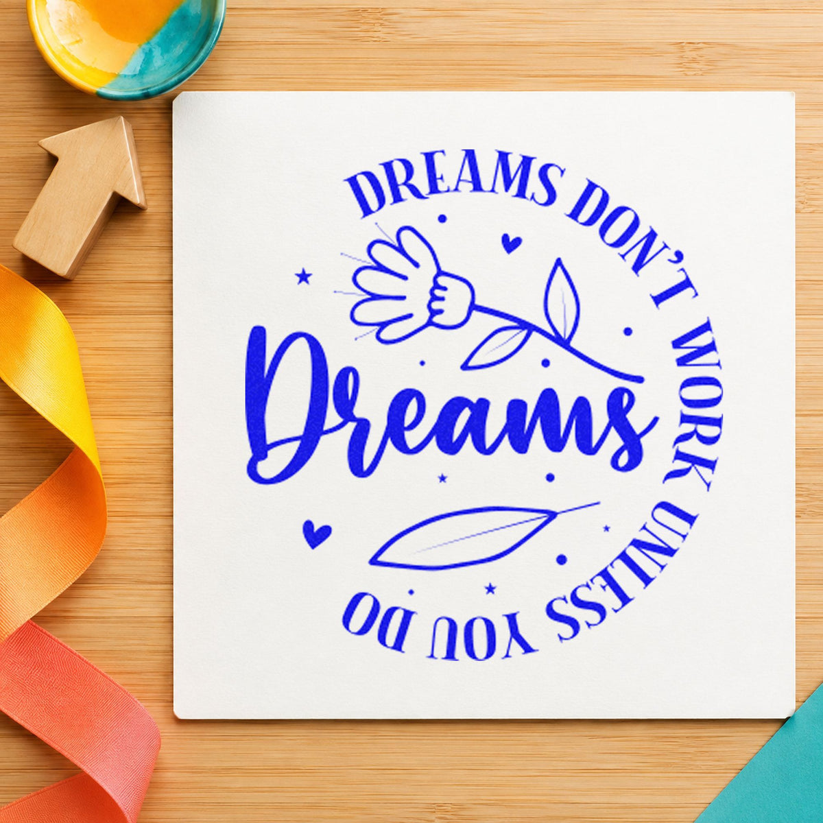 Dreams Don't Work Floral Circle craft stamp imprinted in blue ink on paper, a design suited to framed teaching room.