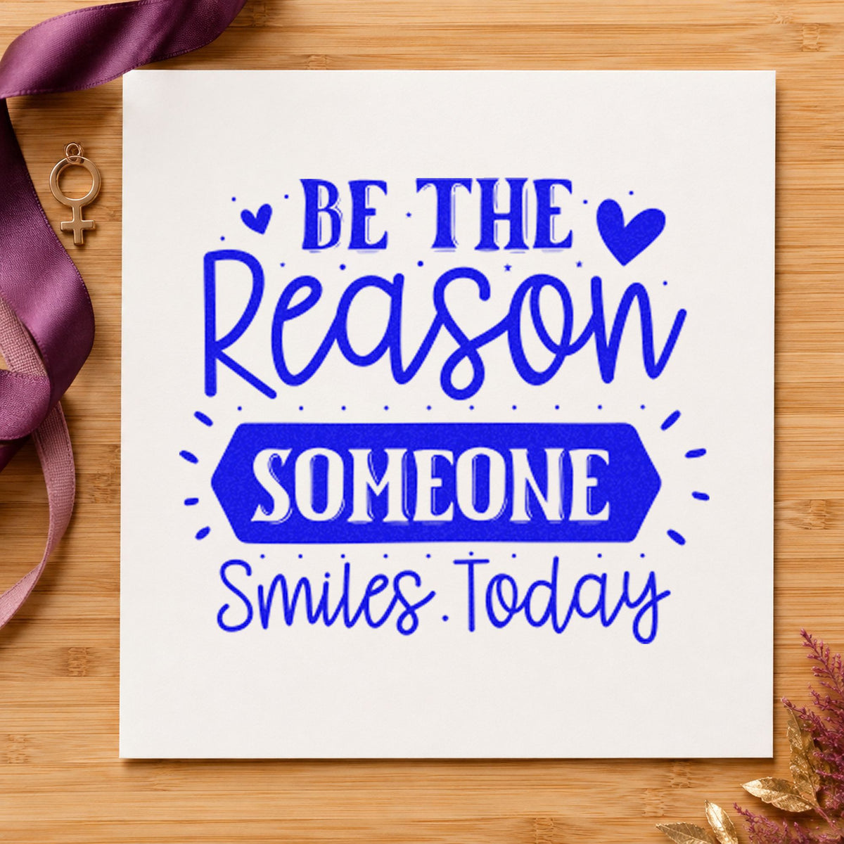 Be Reason Someone Smiles Today craft stamp imprinted in blue ink on paper, a design suited to framed shop window.