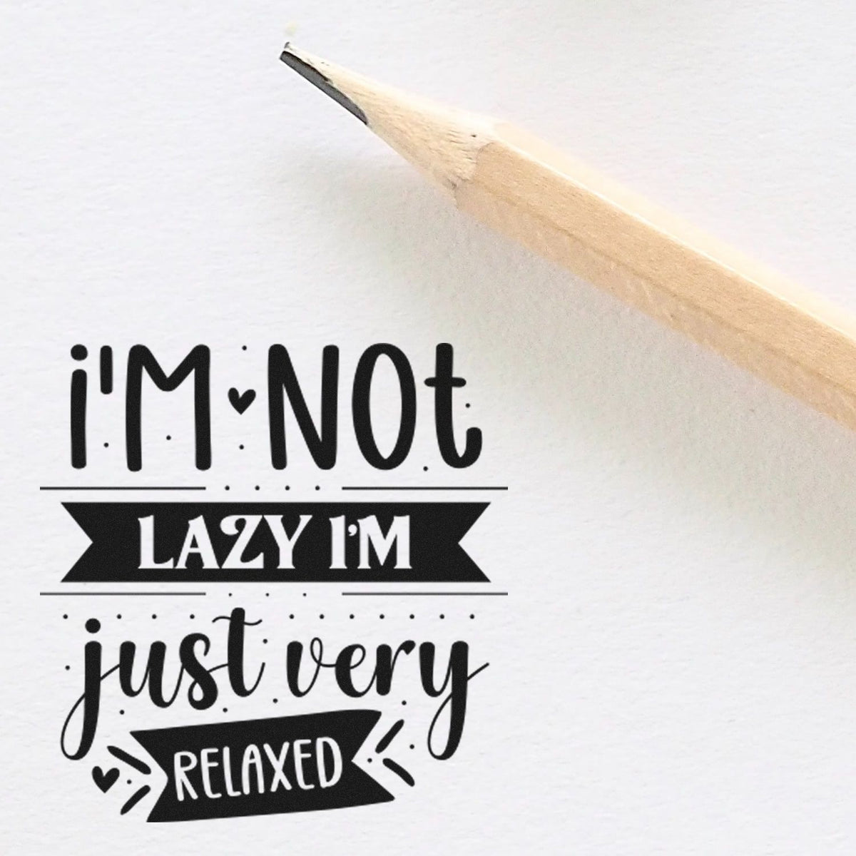 Vintage Pro I'm Not Lazy I'm Just Very Relaxed Premium Wooden Stamp imprint stamped in black ink. The phrase "I'm not lazy I'm just very relaxed" appears with dark banners, small hearts, dots, and rays.