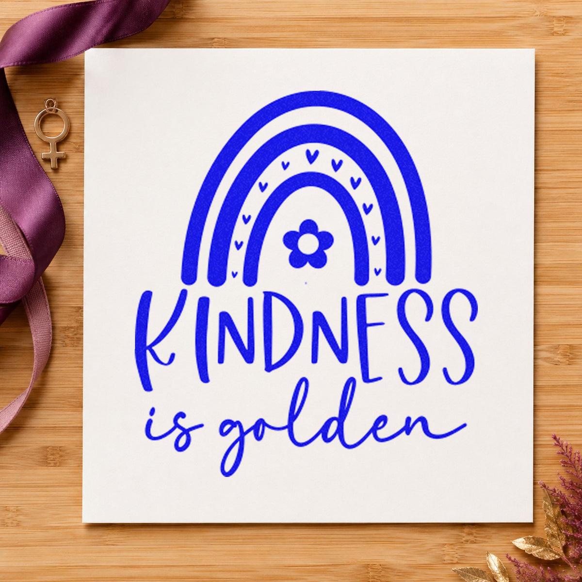 Kindness Is Golden Rainbow craft stamp imprinted in blue ink on paper, a design suited to framed waiting bench.