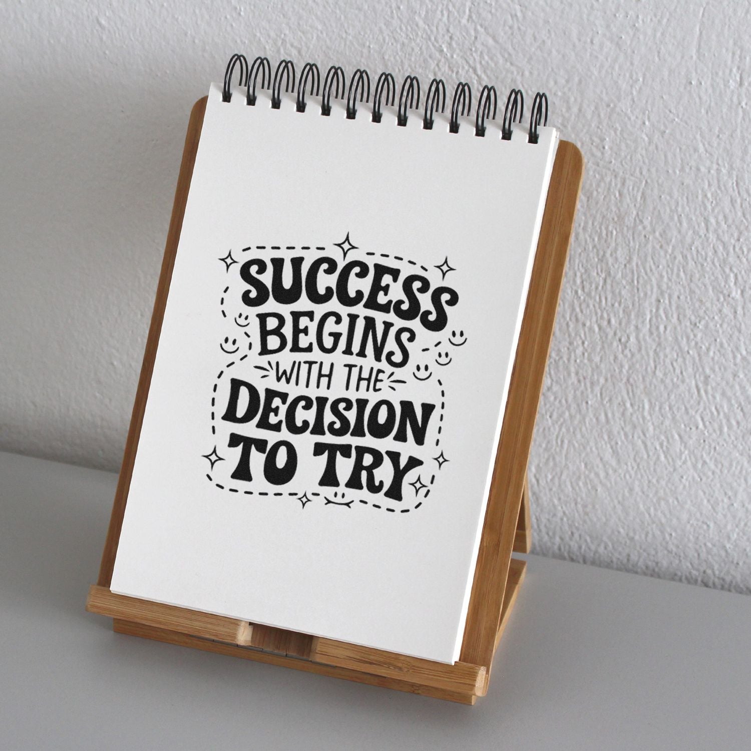 Motivational rubber stamp design reading Success begins with the decision to try on a notebook display.