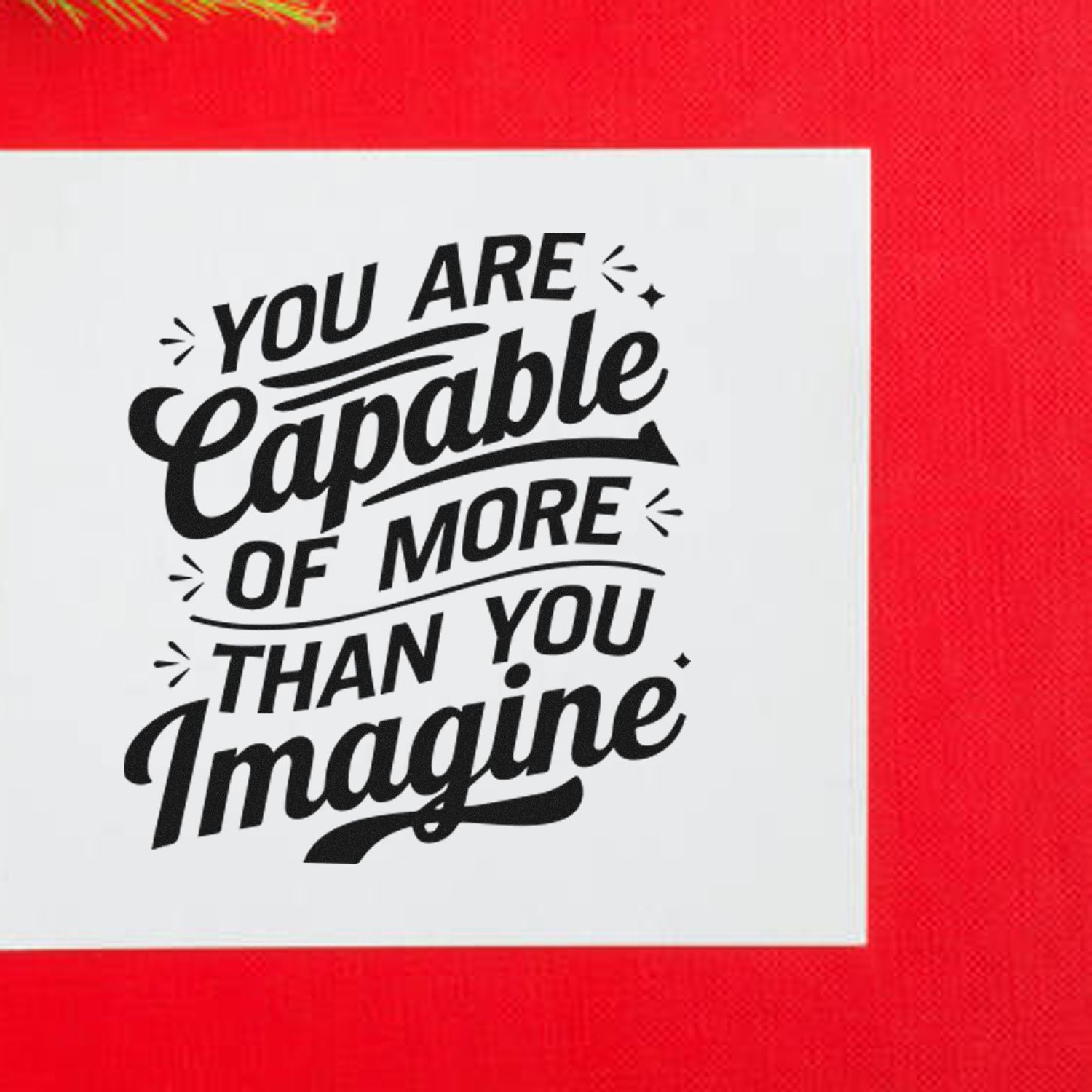 Inspirational rubber stamp with bold quote, You are capable of more than you imagine, in black lettering on a white square background.