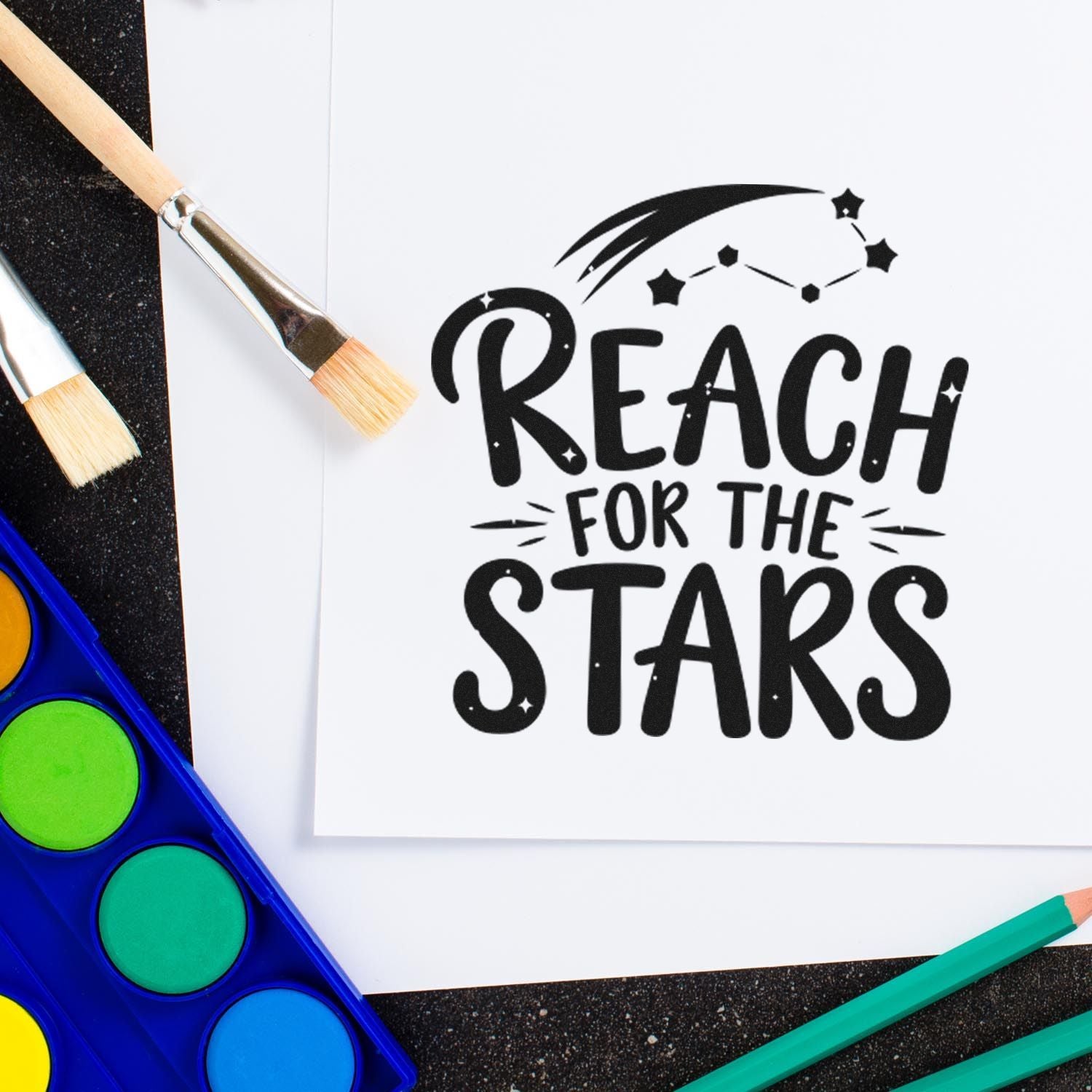 Rubber stamp design reading Reach for the Stars with paintbrushes and watercolor palette for DIY craft projects.