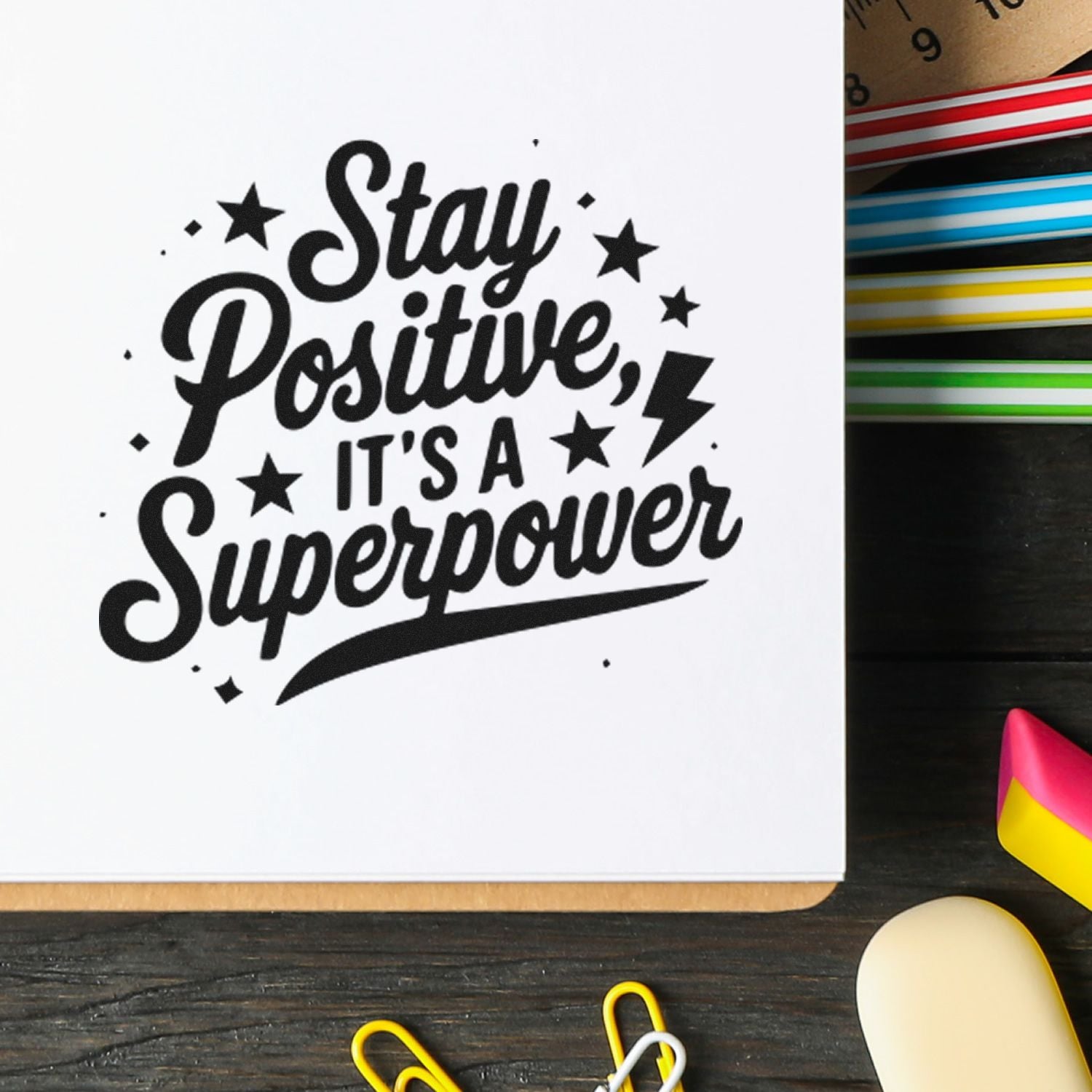 Inspirational rubber stamp reading Stay Positive, Its a Superpower with stars and lightning bolt on notebook.