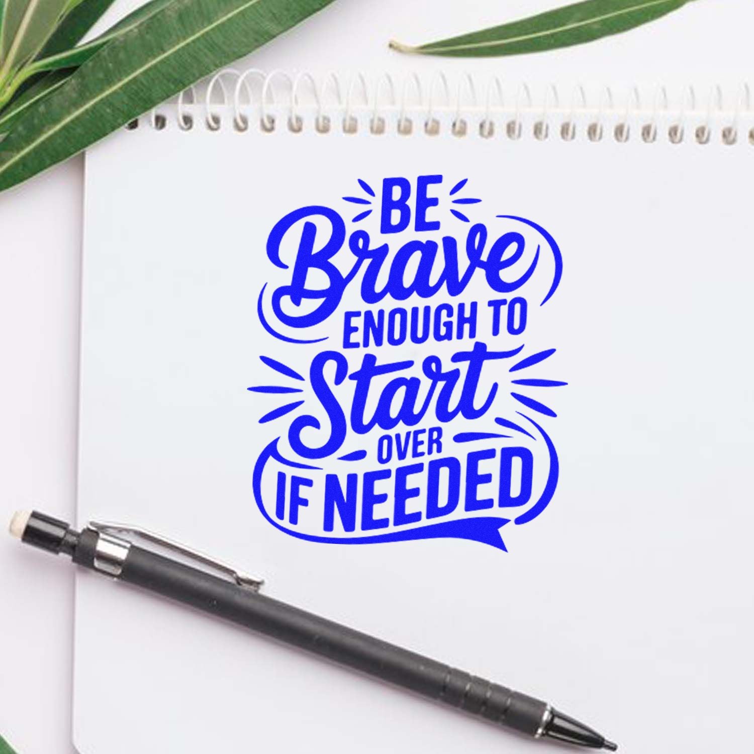 Motivational rubber stamp design reading Be Brave Enough to Start Over If Needed on a notebook with pen.