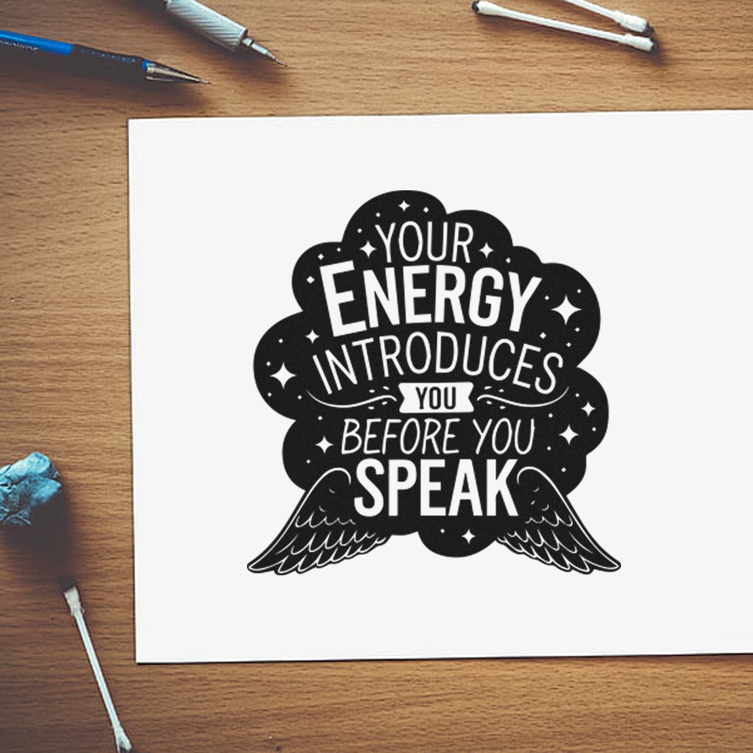 Custom rubber stamp quote design: Your energy introduces you before you speak in bold black with wings on white paper.