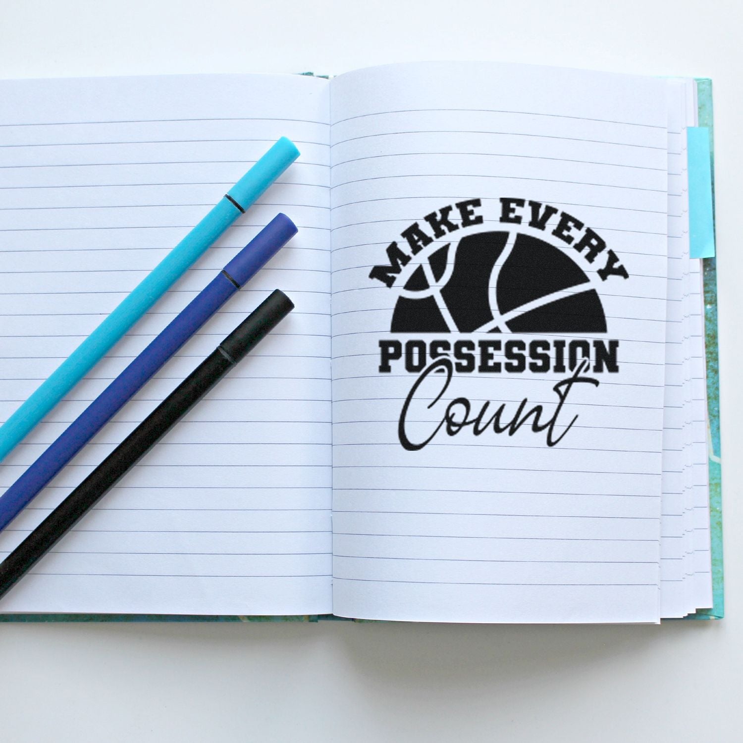 Basketball coach rubber stamp reading Make Every Possession Count on a lined notebook, ideal for sports planning and team motivation.