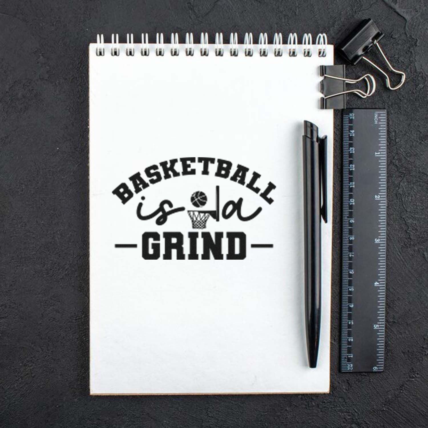 Custom basketball rubber stamp imprint reading Basketball is a Grind on notebook page with pen and ruler.