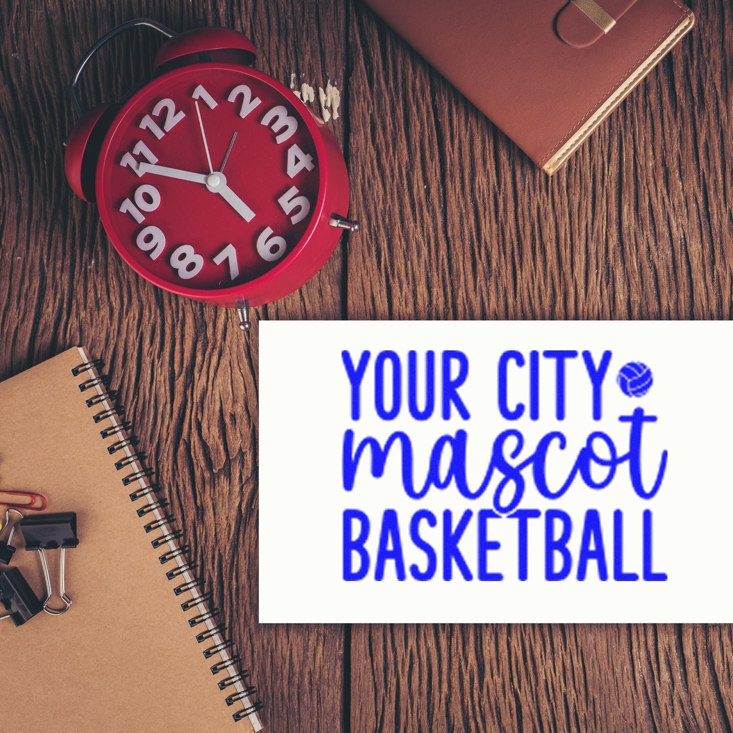 Custom rubber stamp for a basketball team, shown with Your City Mascot Basketball on a desk with clock and notebooks.