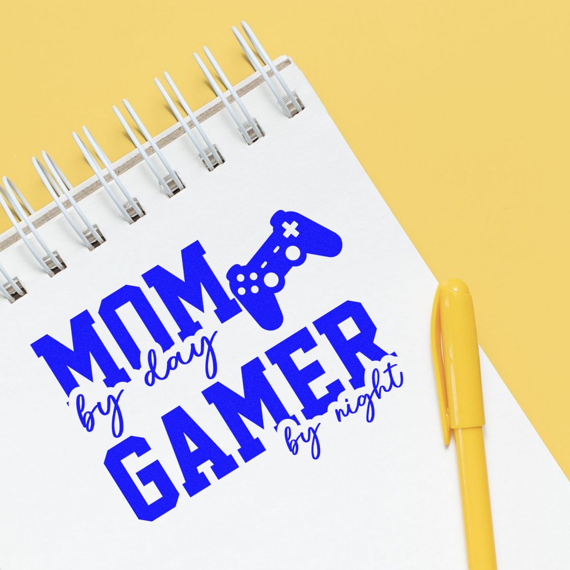 Custom rubber stamp design for gamer mom, reading Mom by day, gamer by night with bold blue lettering and controller icon.