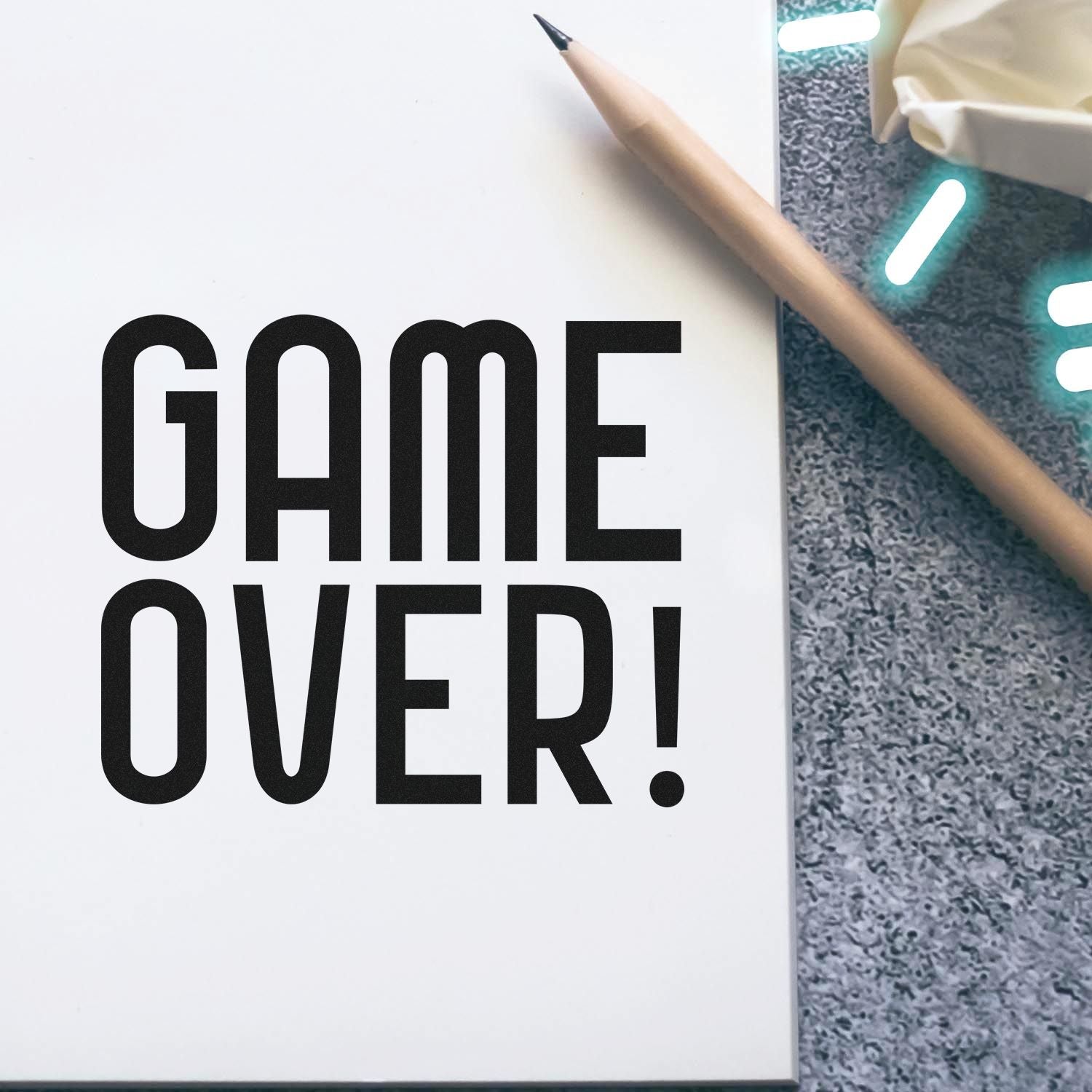 Bold Game Over rubber stamp-style text on a notebook page with pencil, perfect for custom stamps and craft branding.