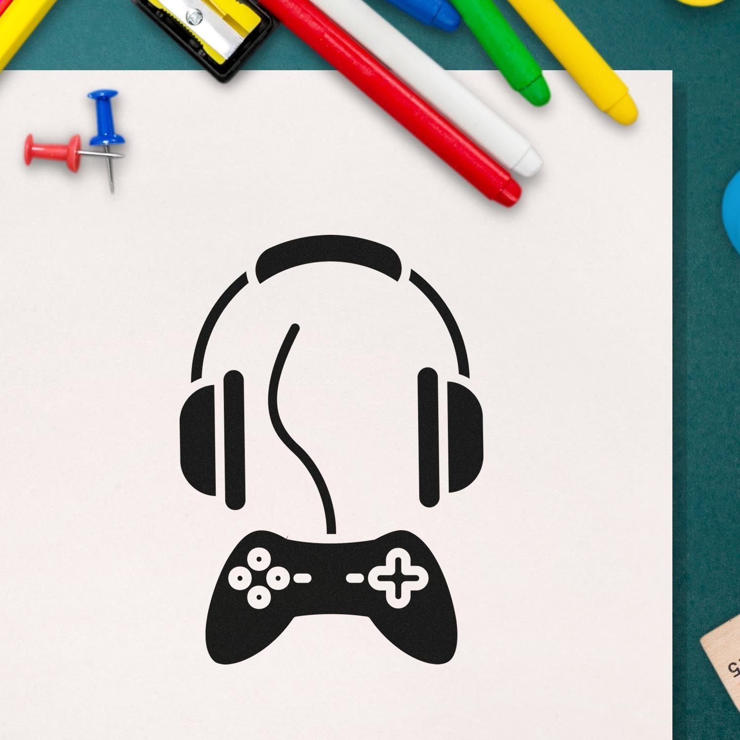 Gaming headset and controller rubber stamp design on paper with colorful markers, ideal for custom gamer-themed stamps.