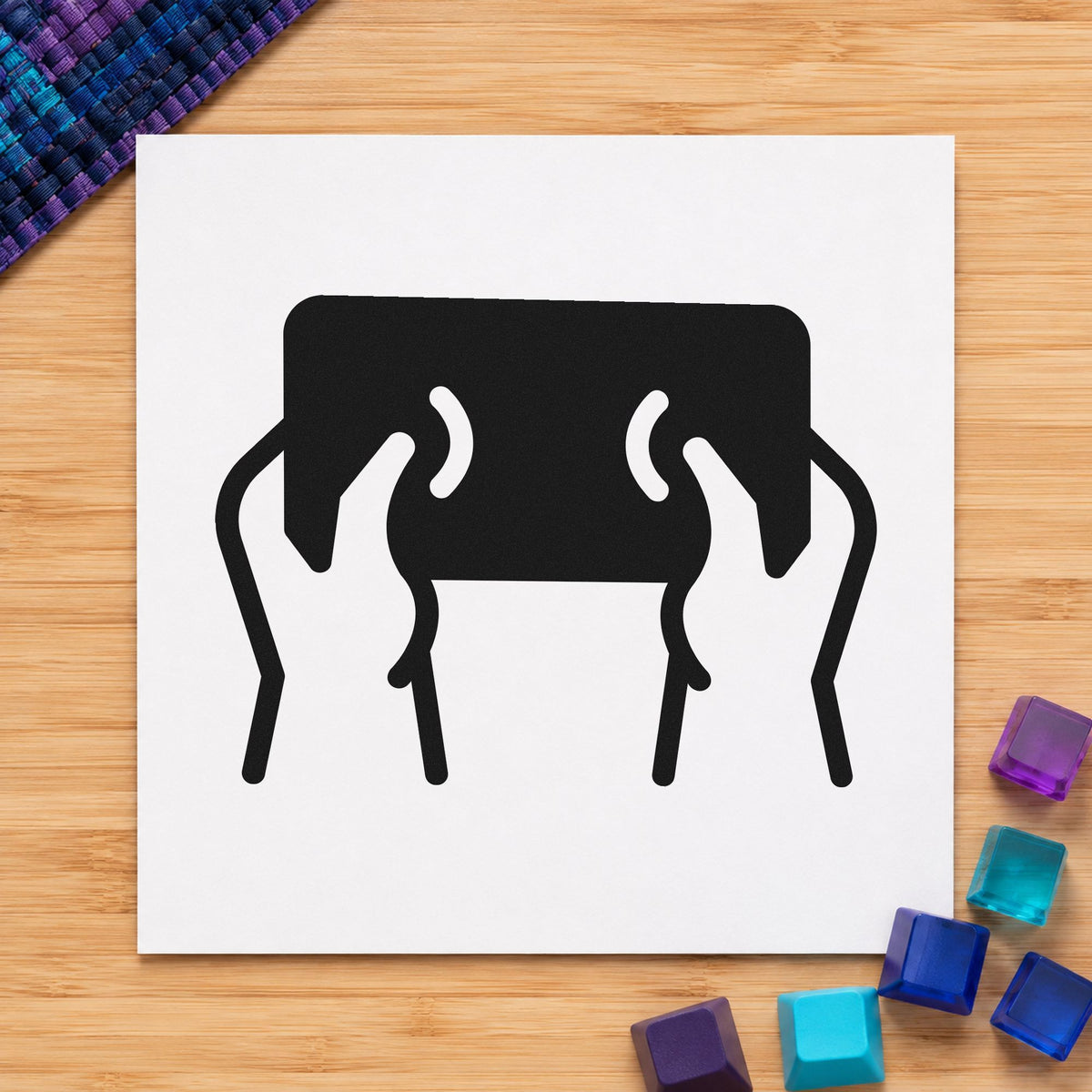 Hands Holding Dark Tablet craft stamp imprint in black ink on a handmade project, one idea being device loan tags.