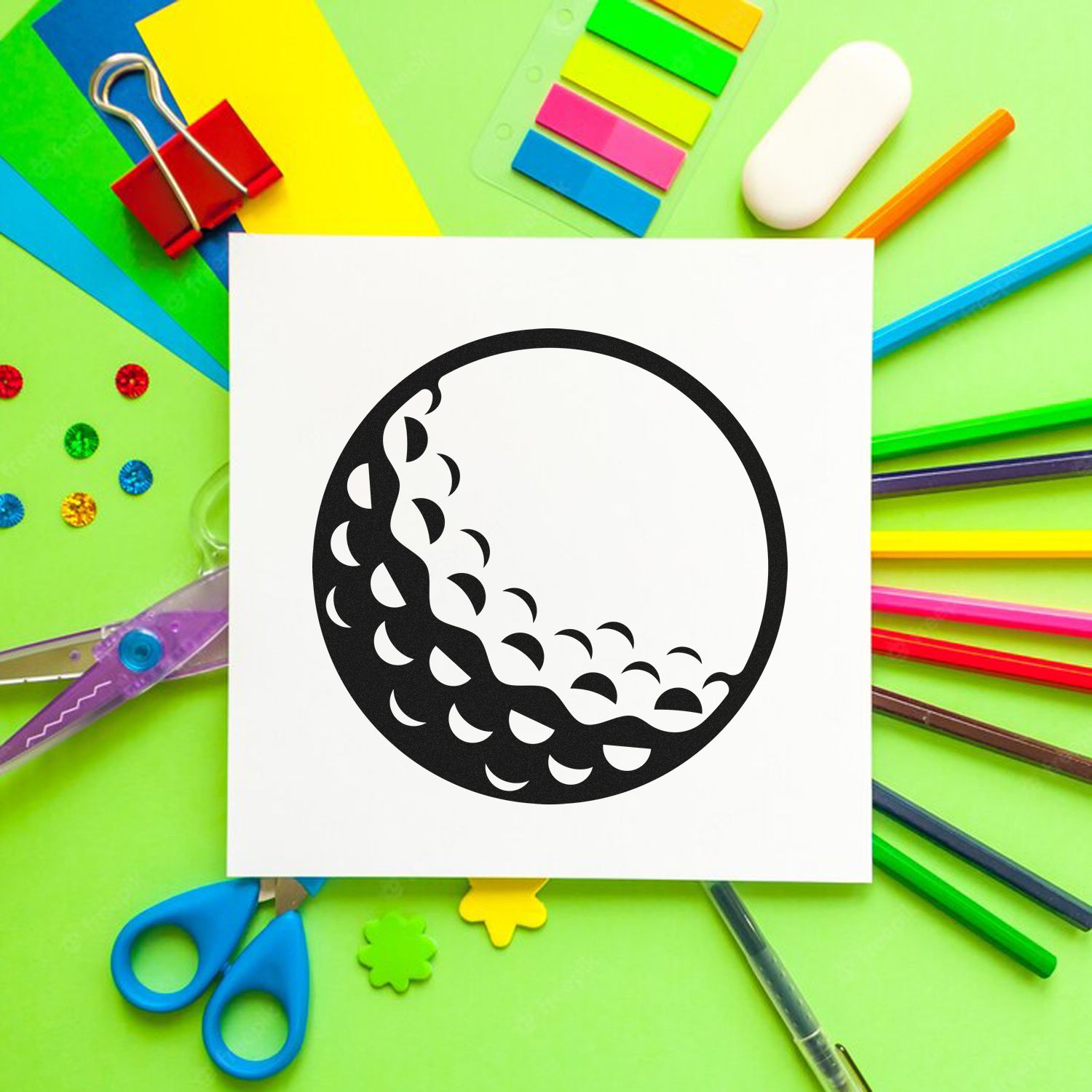 Moon phase rubber stamp design on white paper, surrounded by colorful craft supplies and stationery tools.