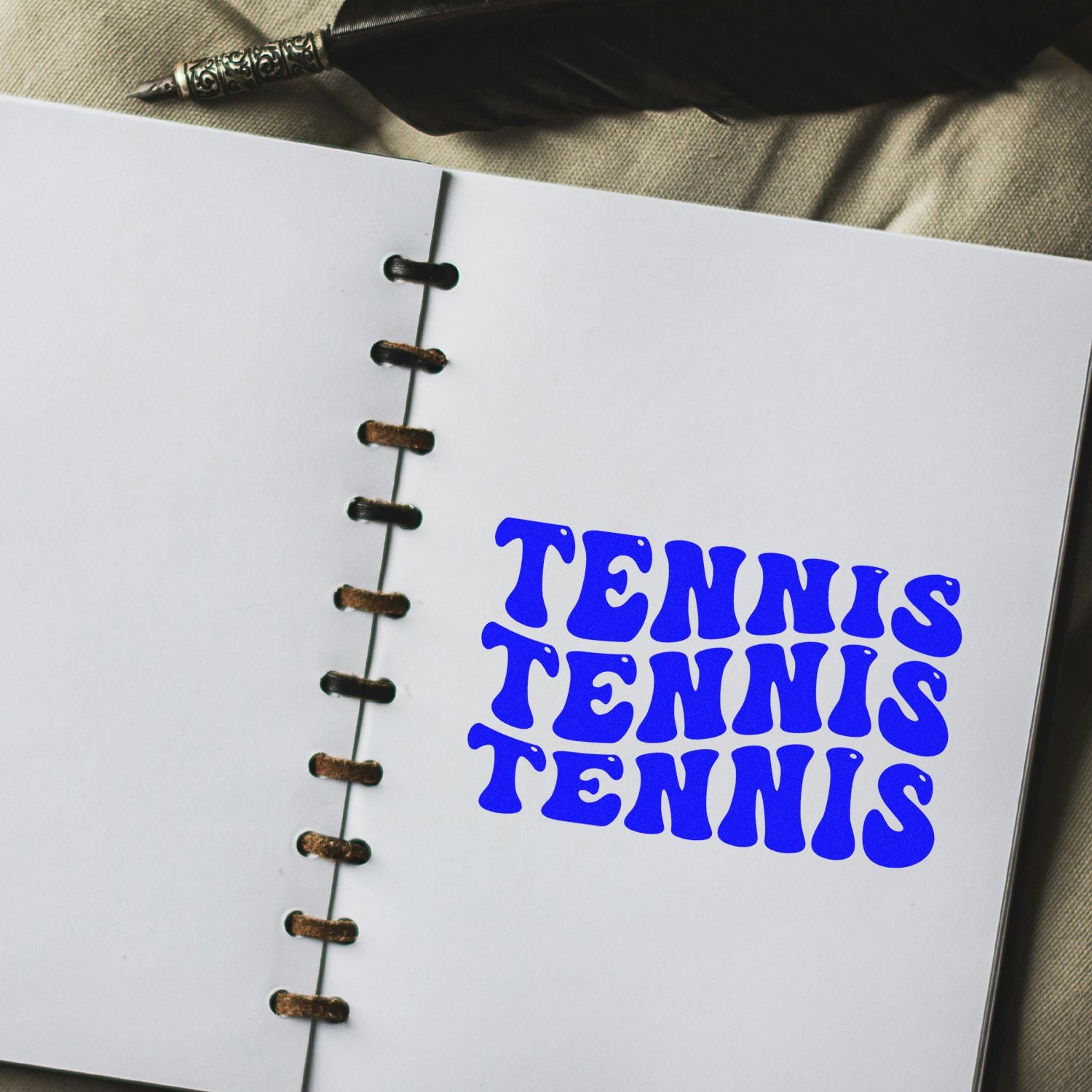 Custom tennis rubber stamp design in bold blue on a notebook page for sports-themed stationery and crafting.