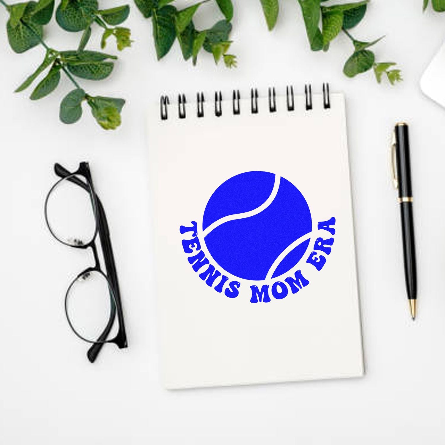Personalized tennis mom era rubber stamp design on notebook mockup with pen and glasses, ideal for custom sports stationery.