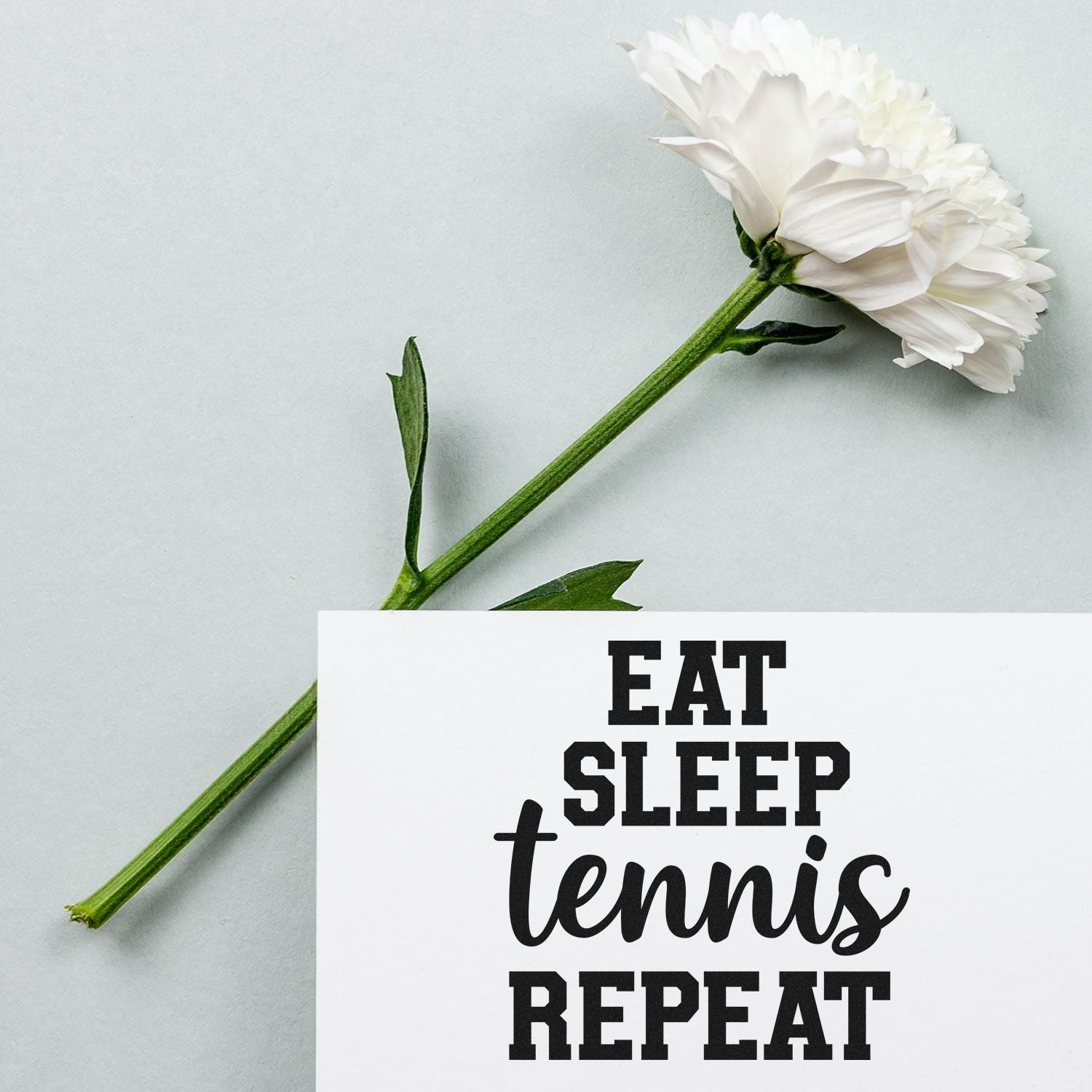 Custom tennis rubber stamp design with Eat Sleep Tennis Repeat slogan beside a white flower.
