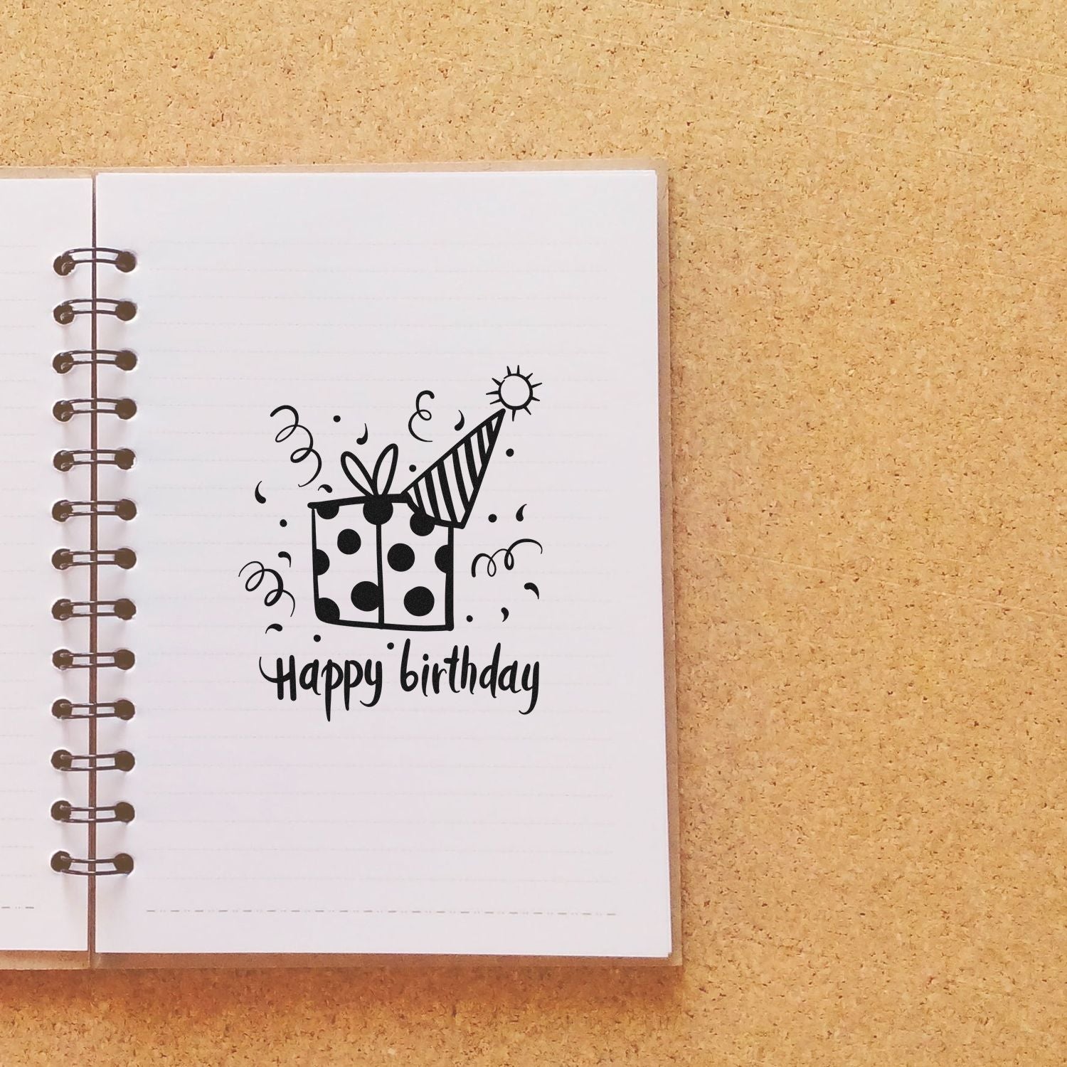 Happy Birthday rubber stamp design with gift box on notebook page, perfect for handmade birthday cards, scrapbooks, and craft projects.