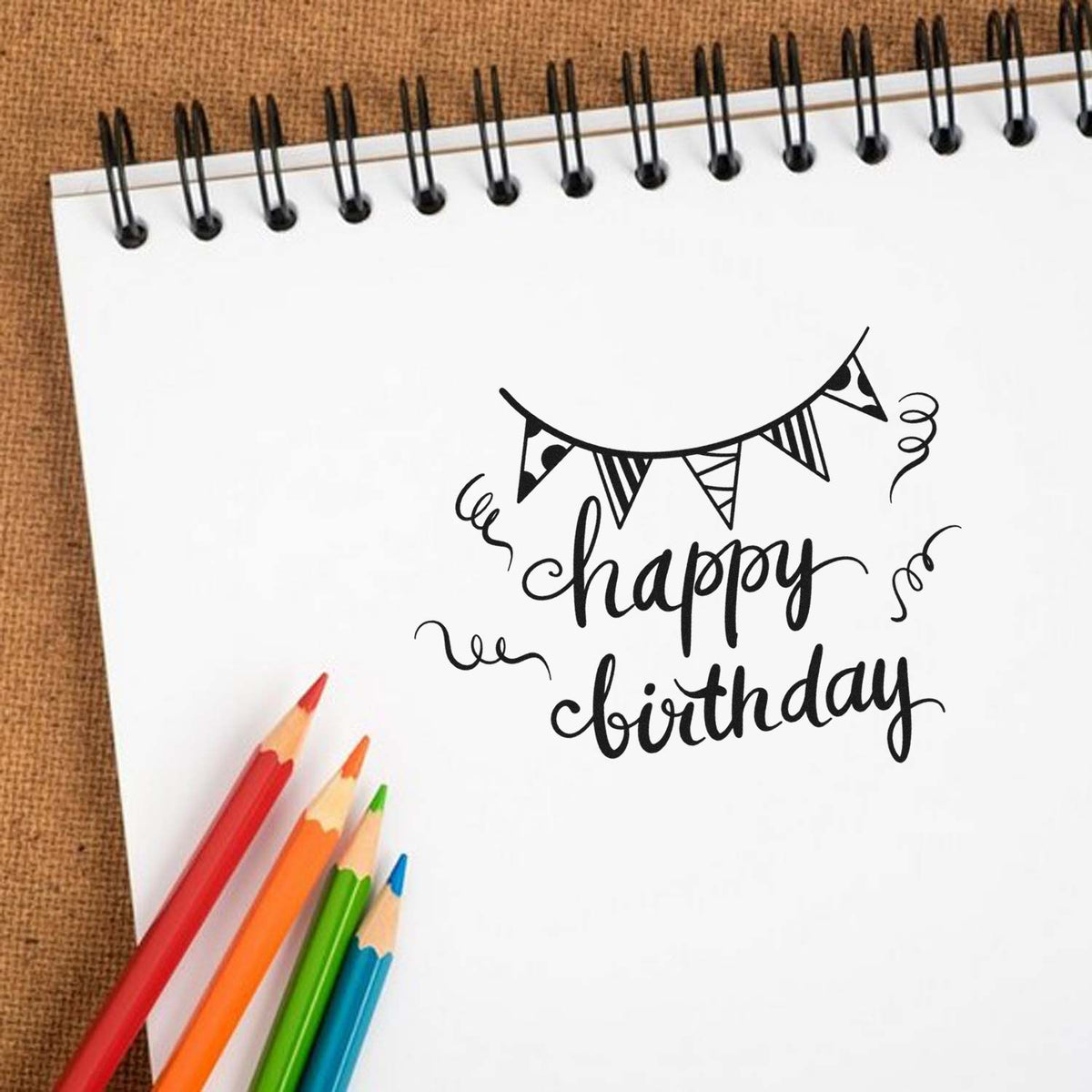 Premium Wooden Birthday Bunting Streamer Script Stamp - Vintage Pro imprint stamped in black ink. Striped pennant bunting hangs above happy birthday surrounded by curling streamers.