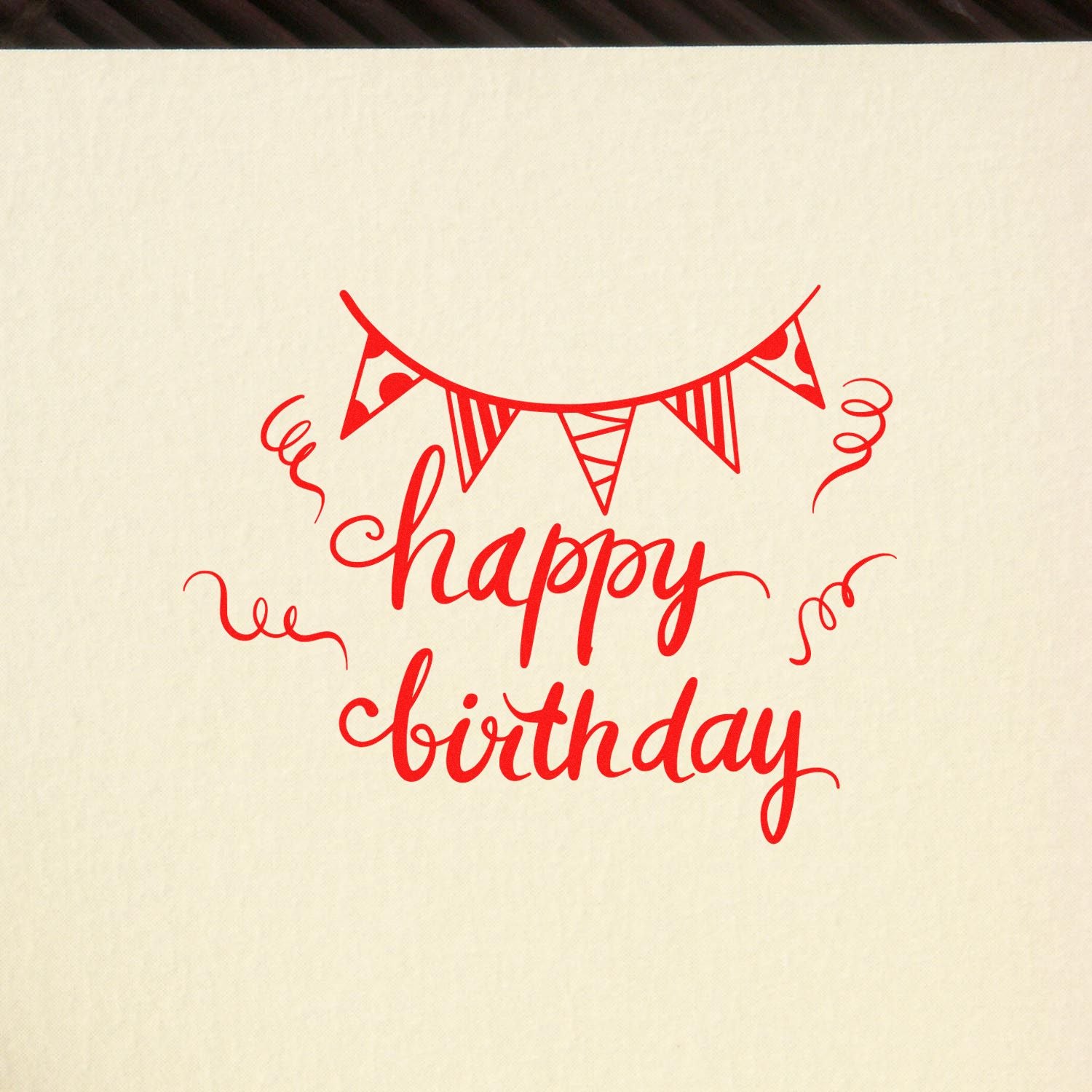 Happy birthday rubber stamp design with festive bunting and confetti swirls in red on a cream background