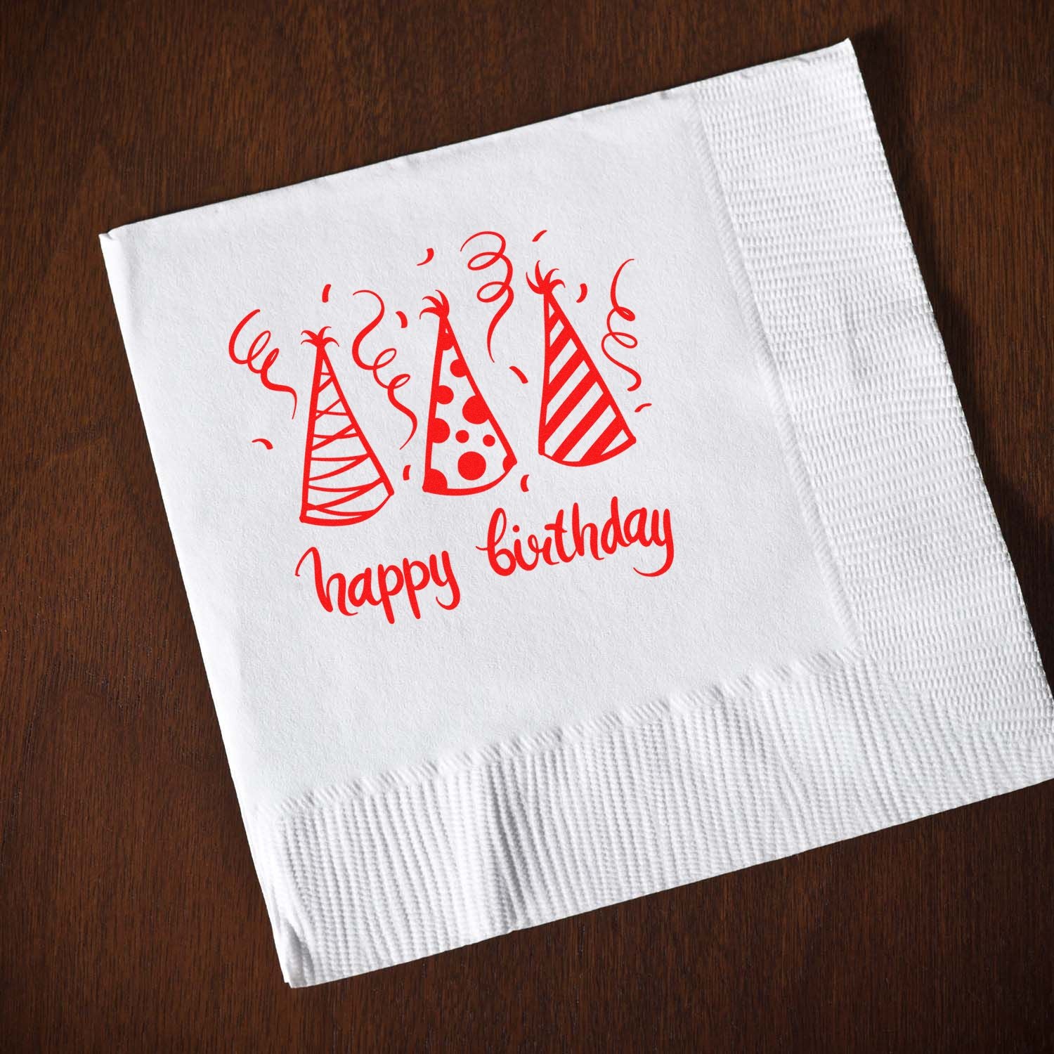 Happy birthday party hat rubber stamp on white napkin, ideal for birthday invitations, cards, and party crafts.
