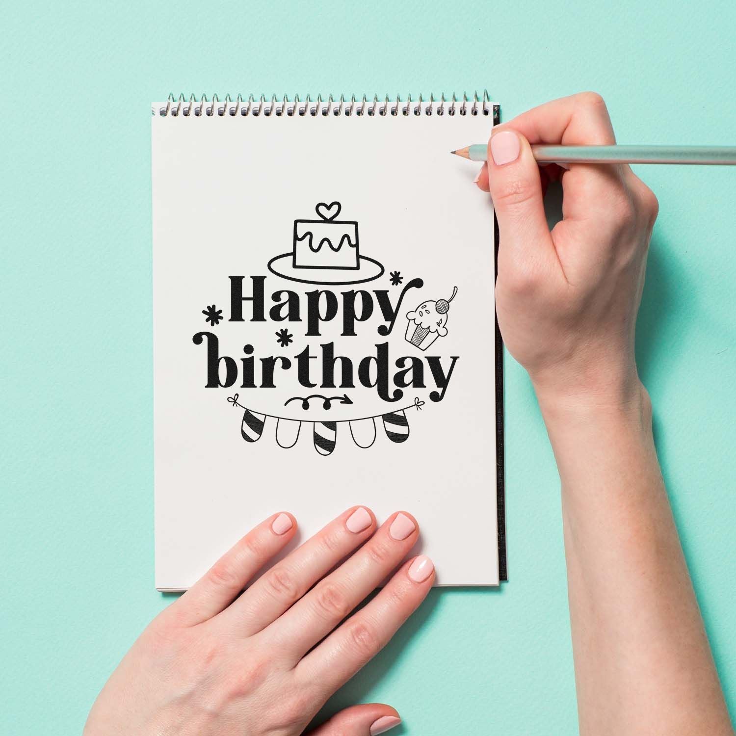 Happy birthday rubber stamp design for card making, shown on a notebook with cake, cupcake and bunting.