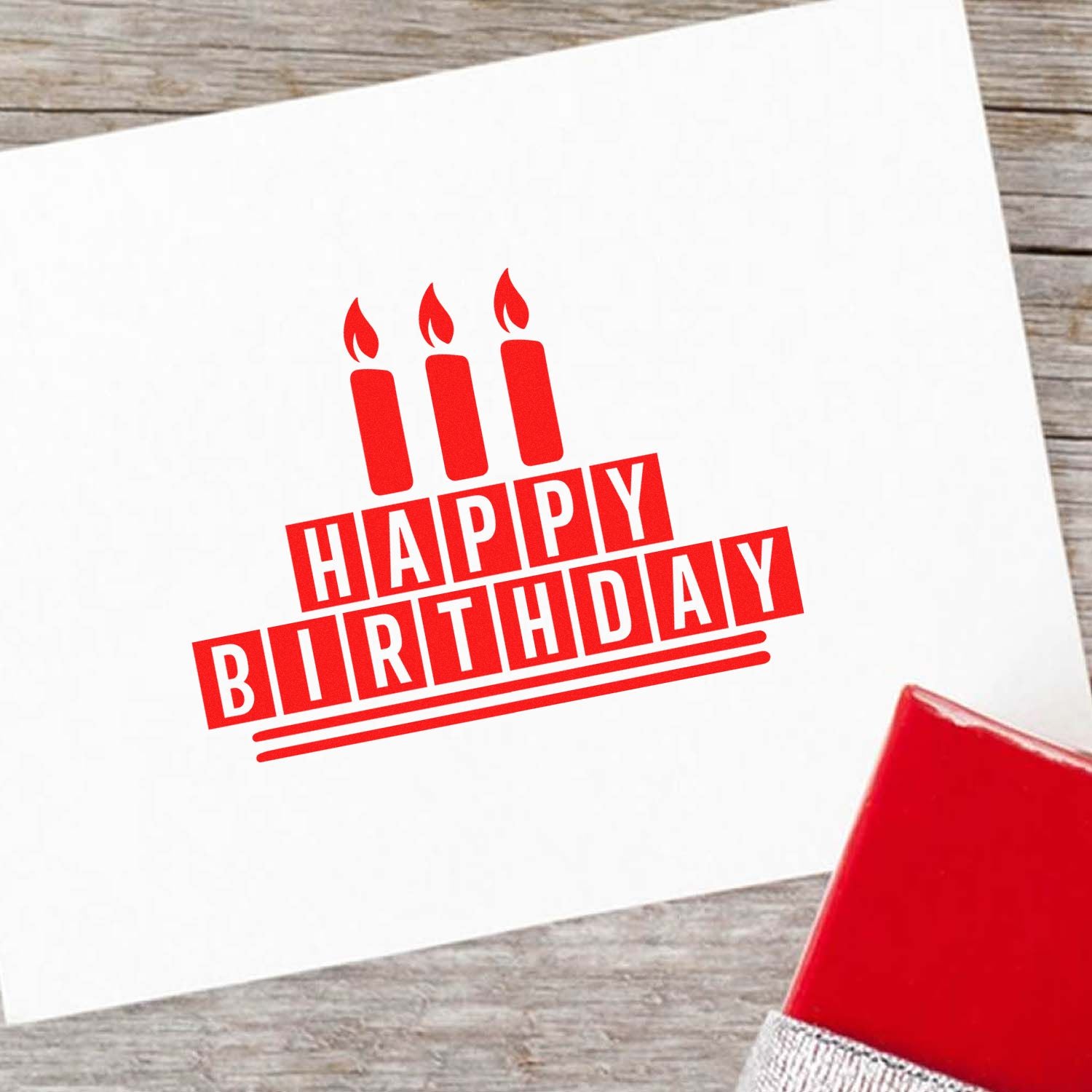 Happy Birthday rubber stamp with candle design printed in red ink on a white card.