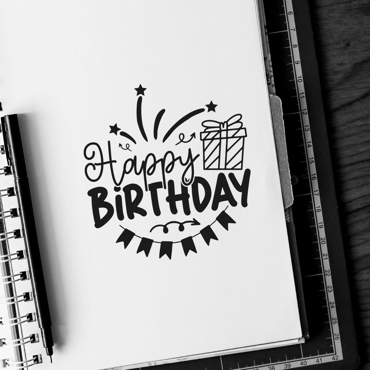 Vintage Pro Happy Birthday Gift Bunting Premium Wooden Stamp imprint stamped in black ink. Happy BIRTHDAY appears with a wrapped gift, starburst fireworks, and dark pennant bunting.