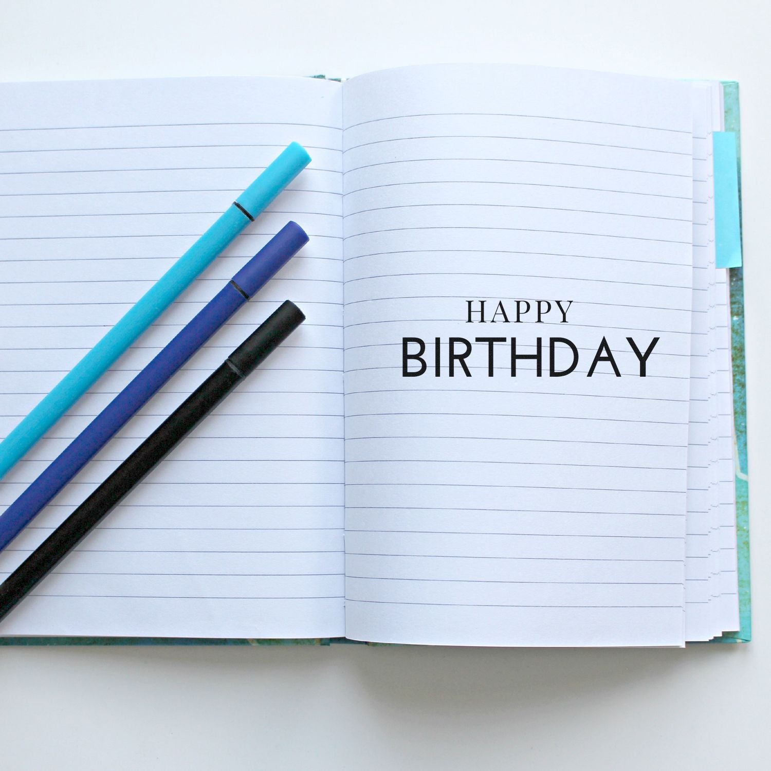 Happy Birthday rubber stamp on open lined notebook with pens, showcasing a custom birthday stamp design for cards and journaling.