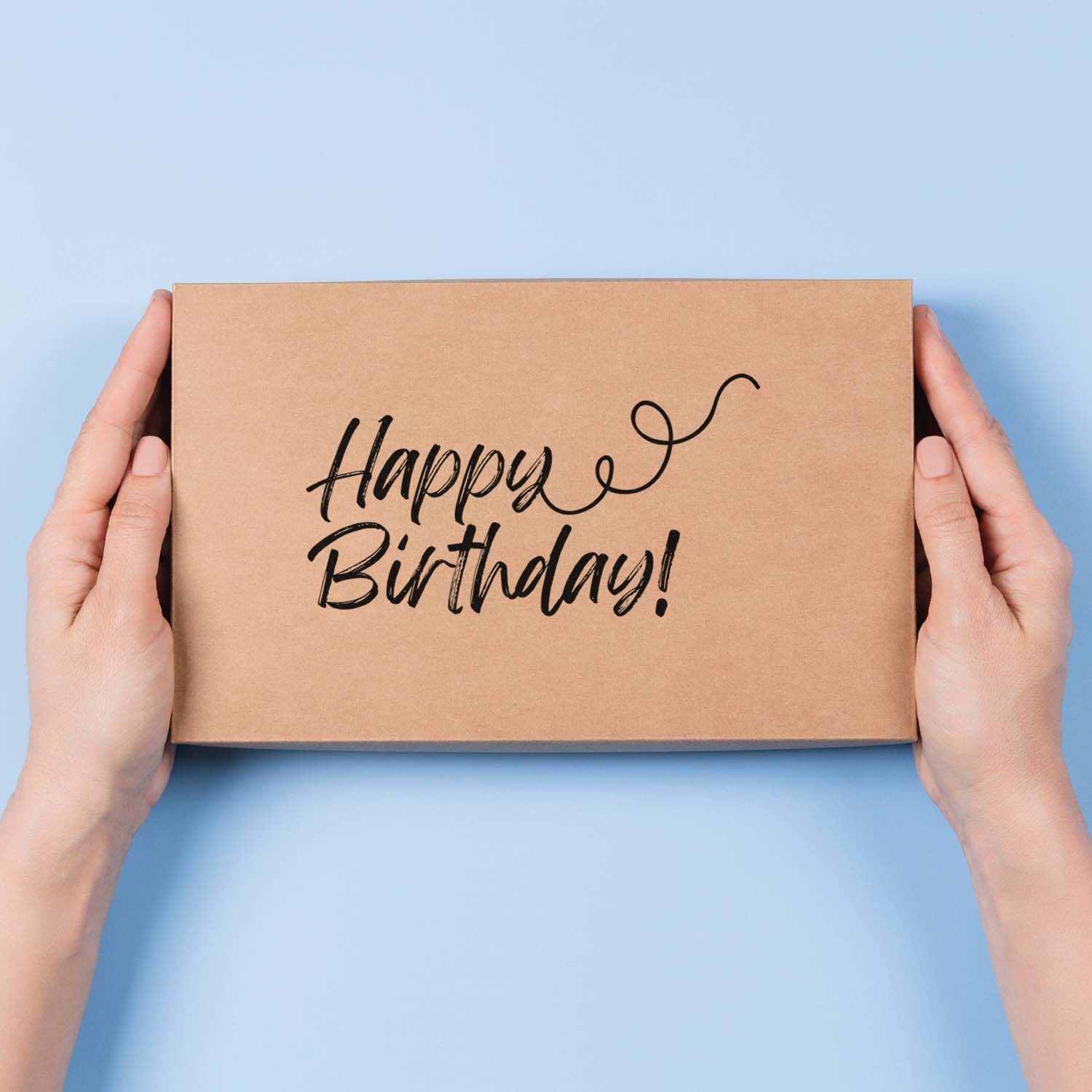 Happy Birthday rubber stamp on kraft gift box held in hands, ideal for custom birthday packaging and gift wrapping.