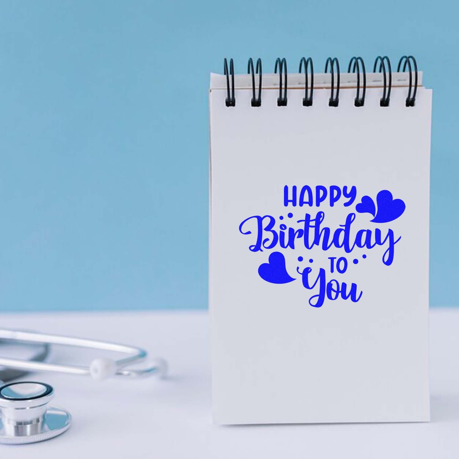 Happy Birthday to You rubber stamp design on a notepad, featuring blue heart accents for handmade card making.
