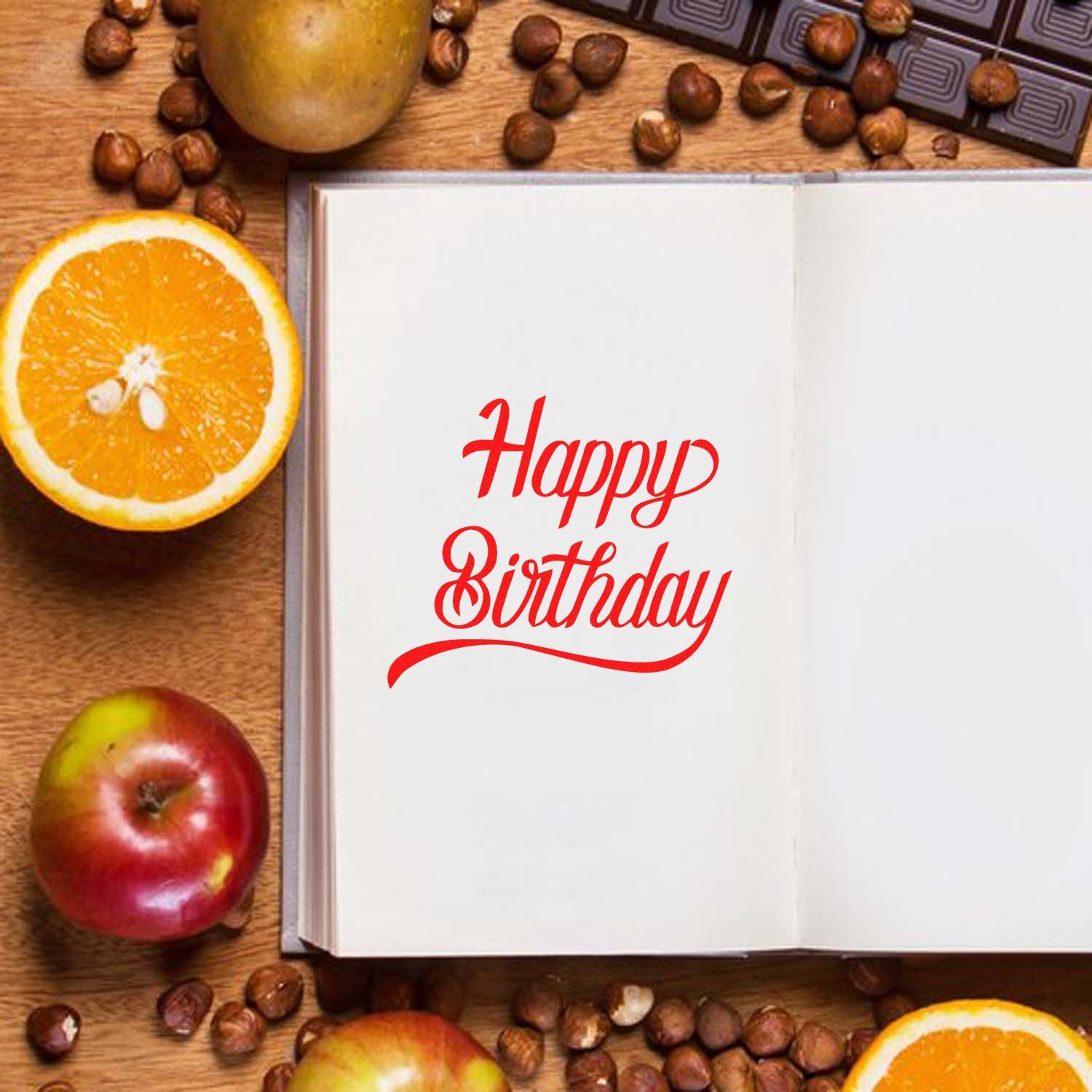 Happy Birthday rubber stamp design in red script on open notebook with fruit and coffee beans.