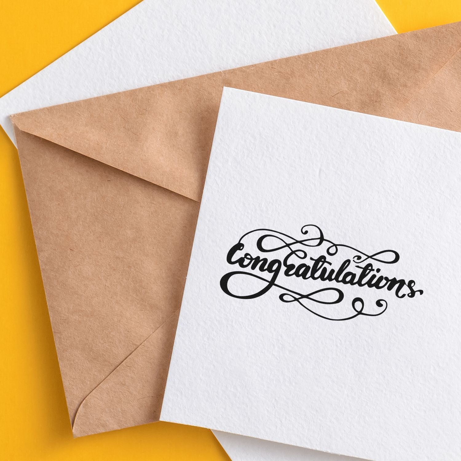 Congratulations calligraphy rubber stamp on white card beside kraft envelope for wedding and celebration mailers.