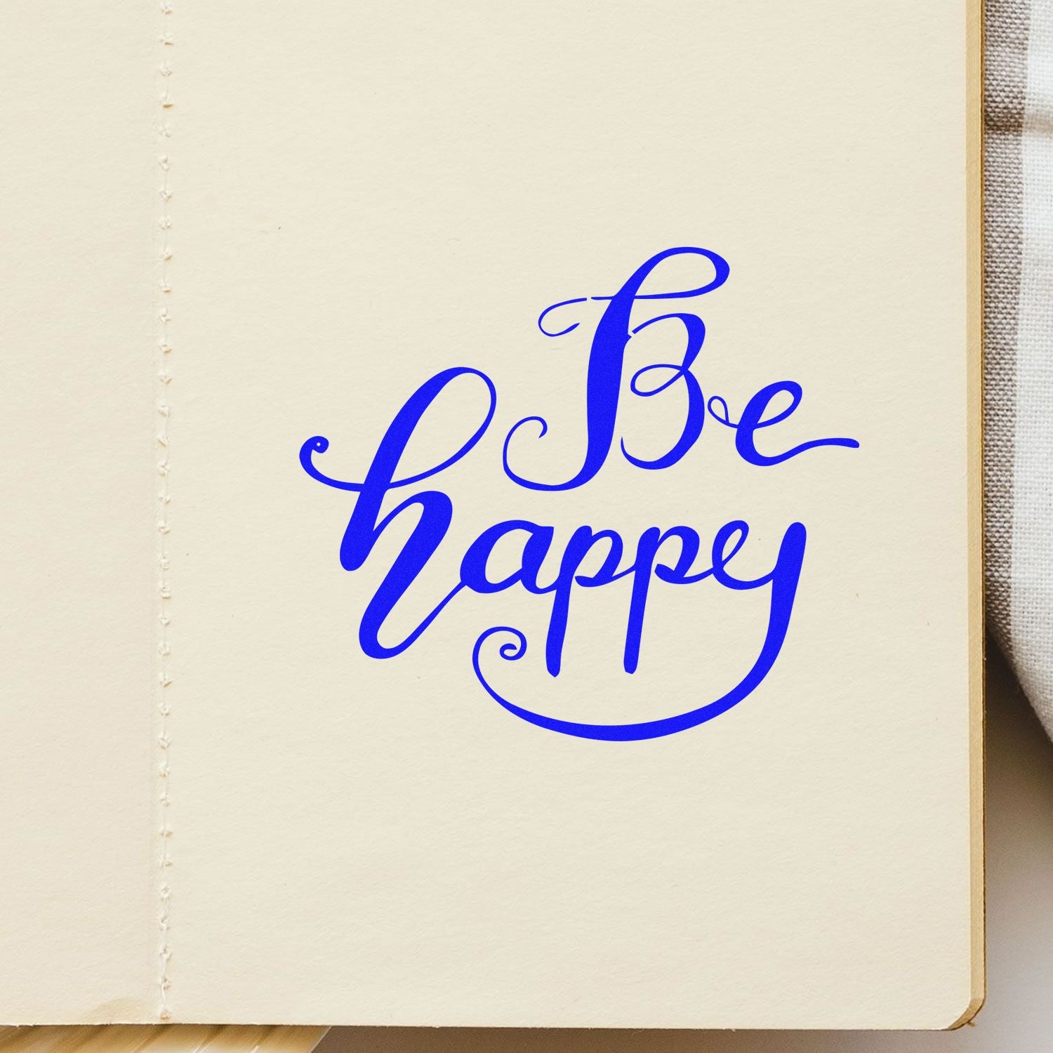 Be Happy script rubber stamp impression in blue ink on paper, perfect for custom motivational stationery and craft projects.