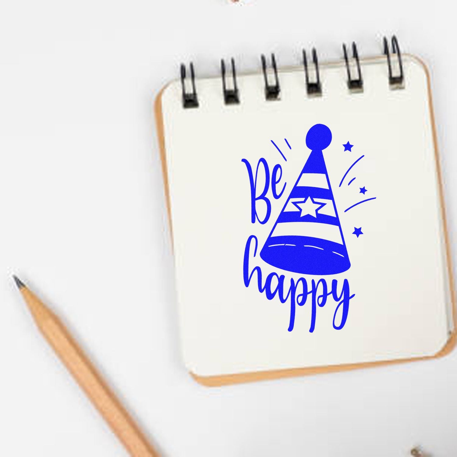 Blue Be happy party hat rubber stamp design on a notebook, perfect for DIY crafts, journals, and greeting cards.