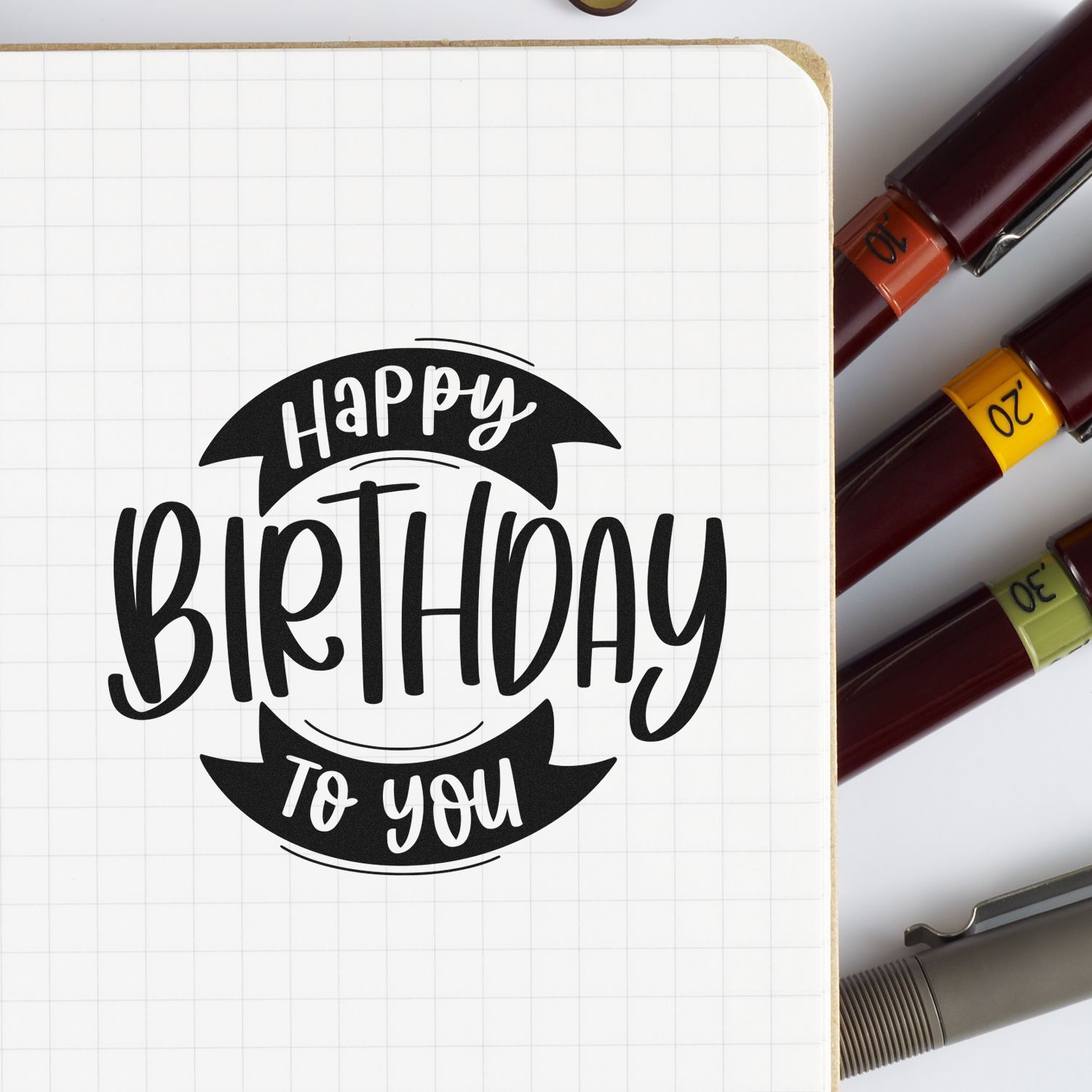 Happy Birthday to You rubber stamp design on grid paper with marker pens, perfect for custom birthday card crafting.
