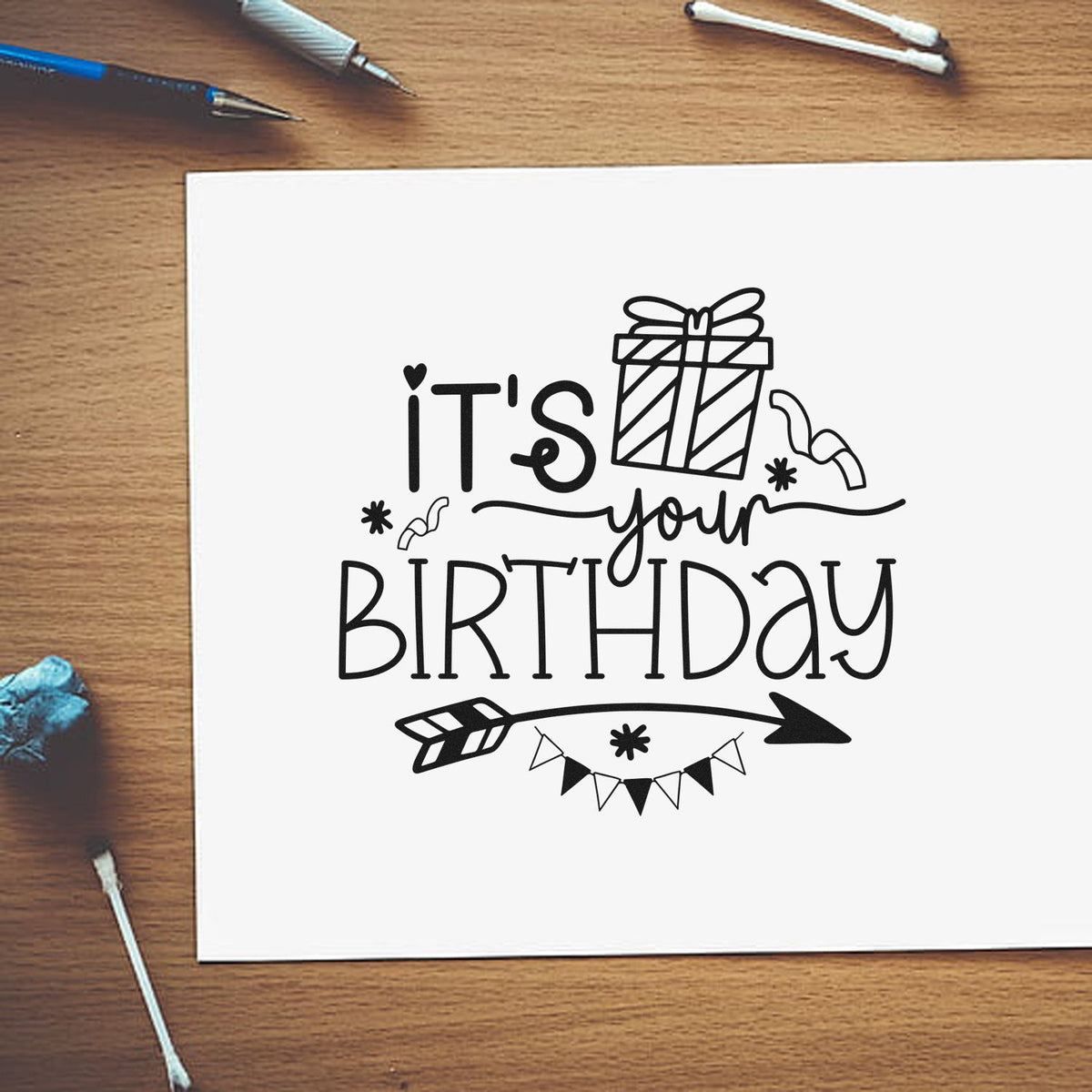 Premium Wooden Your Birthday Gift Arrow Bunting Stamp - Vintage Pro imprint stamped in black ink. IT'S your BIRTHDAY appears with a wrapped gift, small doodles, a right-pointing arrow, and pennant bunting.